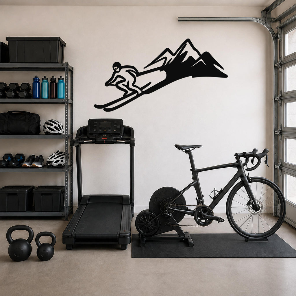 Black metal skier and mountain wall art silhouette mounted on a garage wall above a treadmill and bicycle.
