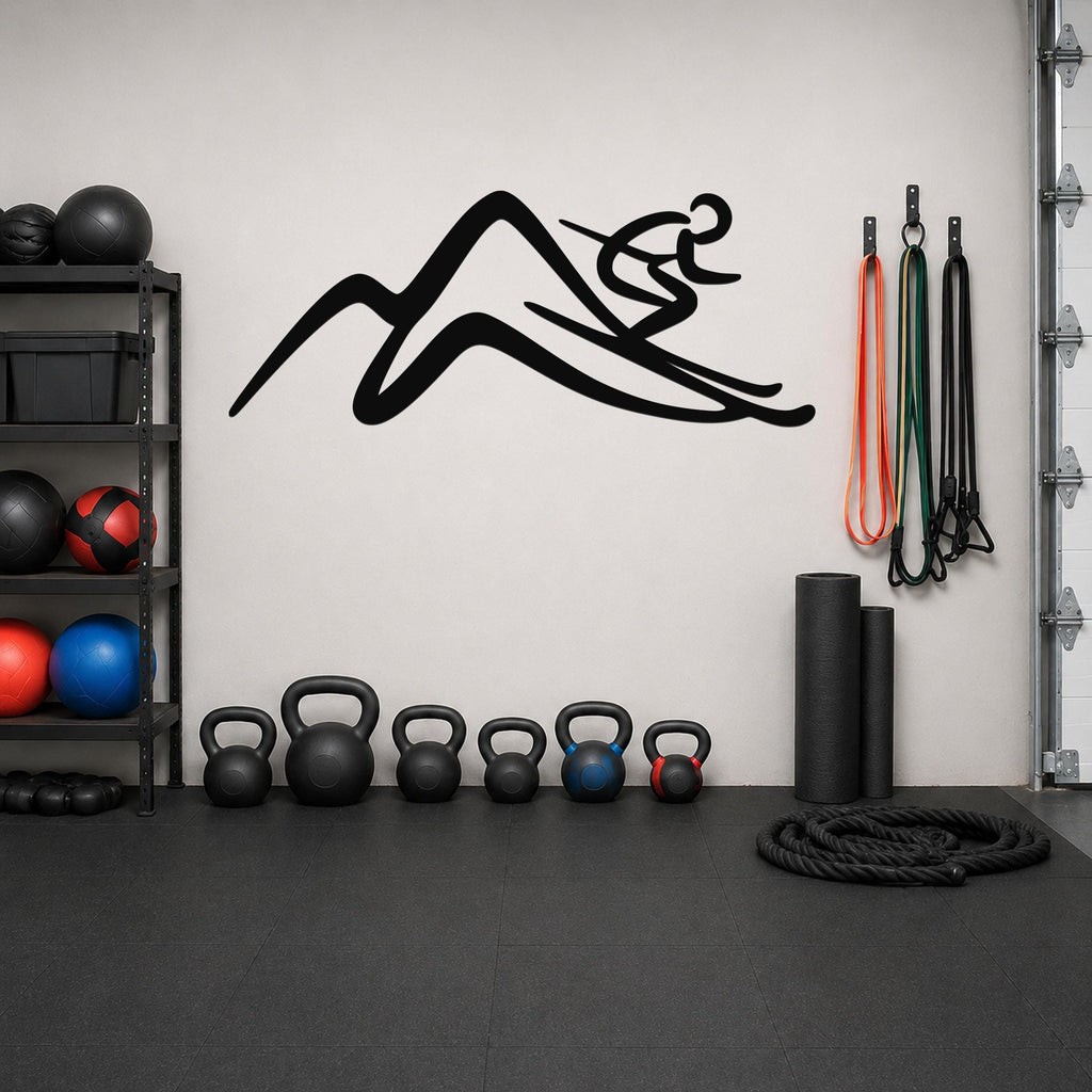 Black metal wall art with a skier silhouette above a mountain, mounted on a light gray wall above a row of kettlebells in a home gym.