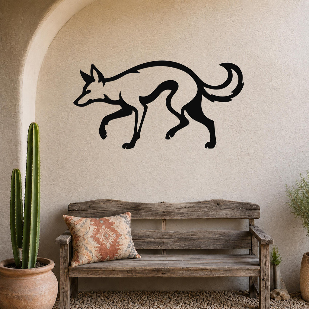 Black metal coyote wall art silhouette mounted on a beige stucco wall above a wooden bench in a rustic patio setting.