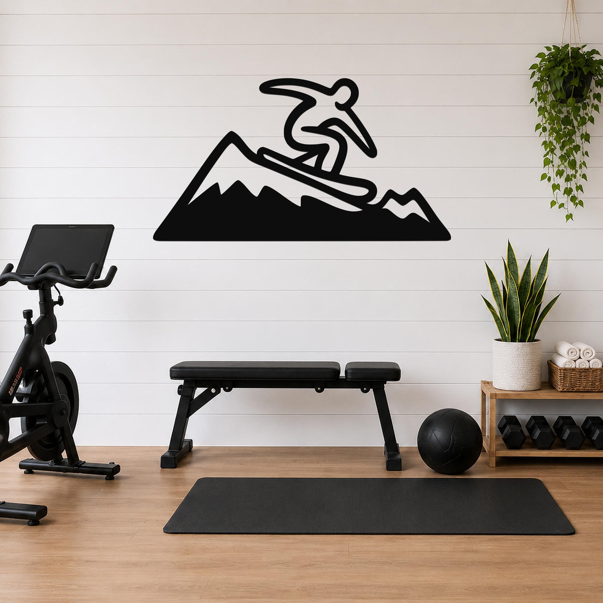 Black metal wall art silhouette of a snowboarder on a mountain, mounted on a white shiplap wall above a workout bench in a home gym.
