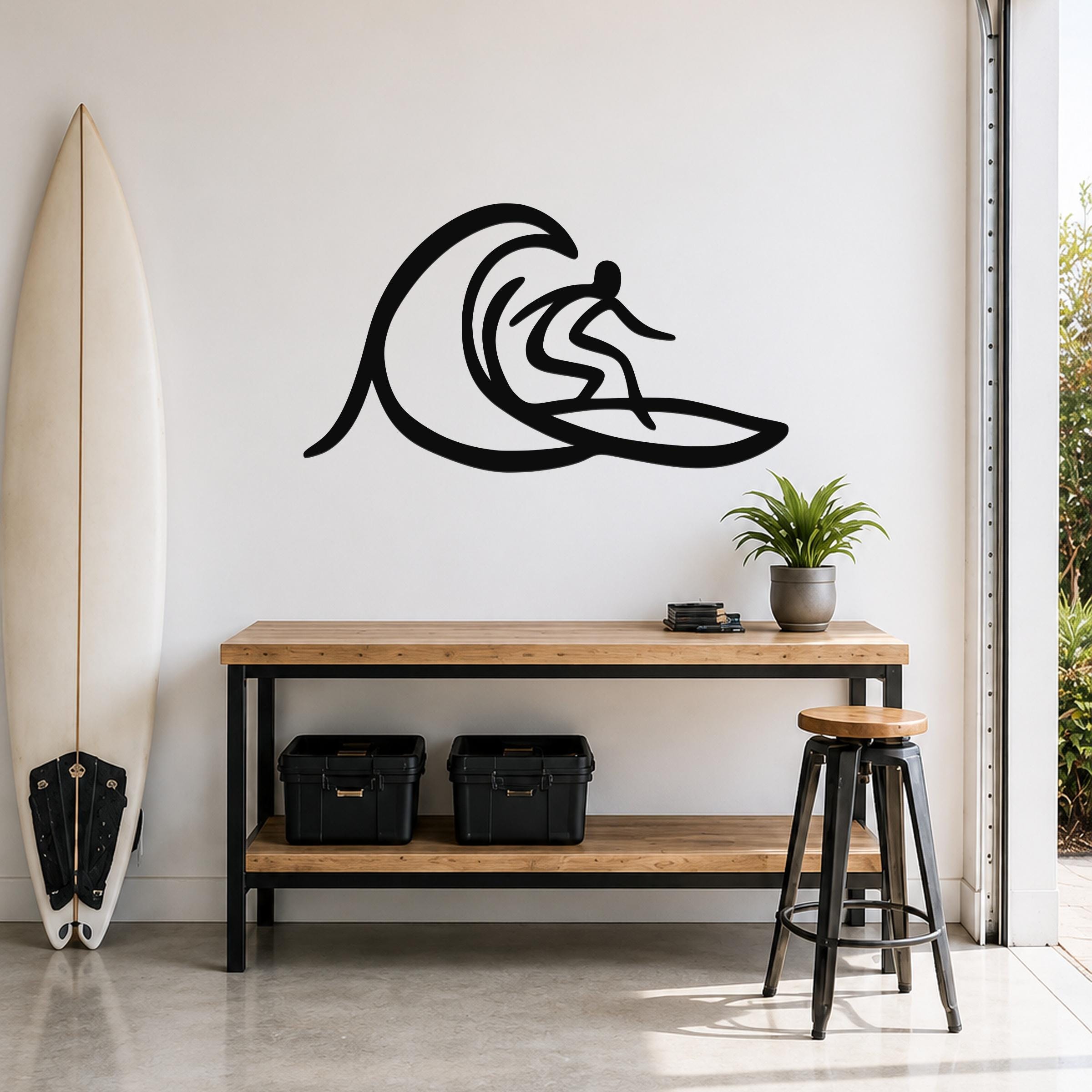 Black metal surfer wall art with wave silhouette cutout, mounted above a wooden console table in a modern entryway.