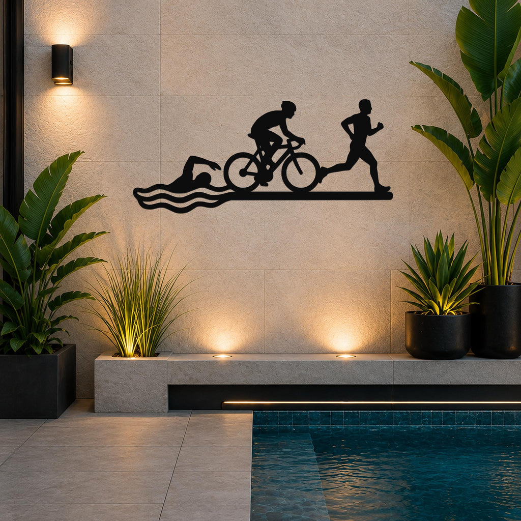 Black metal triathlon wall art with swim, bike, and run silhouettes, mounted on a tiled wall above a poolside planter.