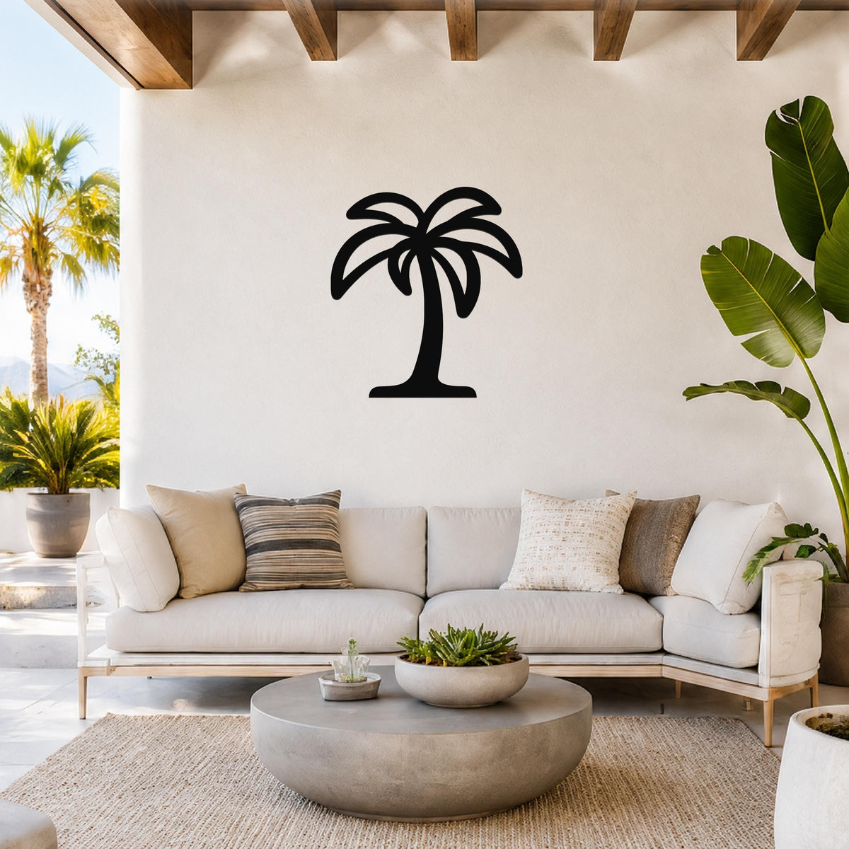 Black metal palm tree wall art with a silhouette design, mounted on a white wall above a light-colored sofa in a bright living room.
