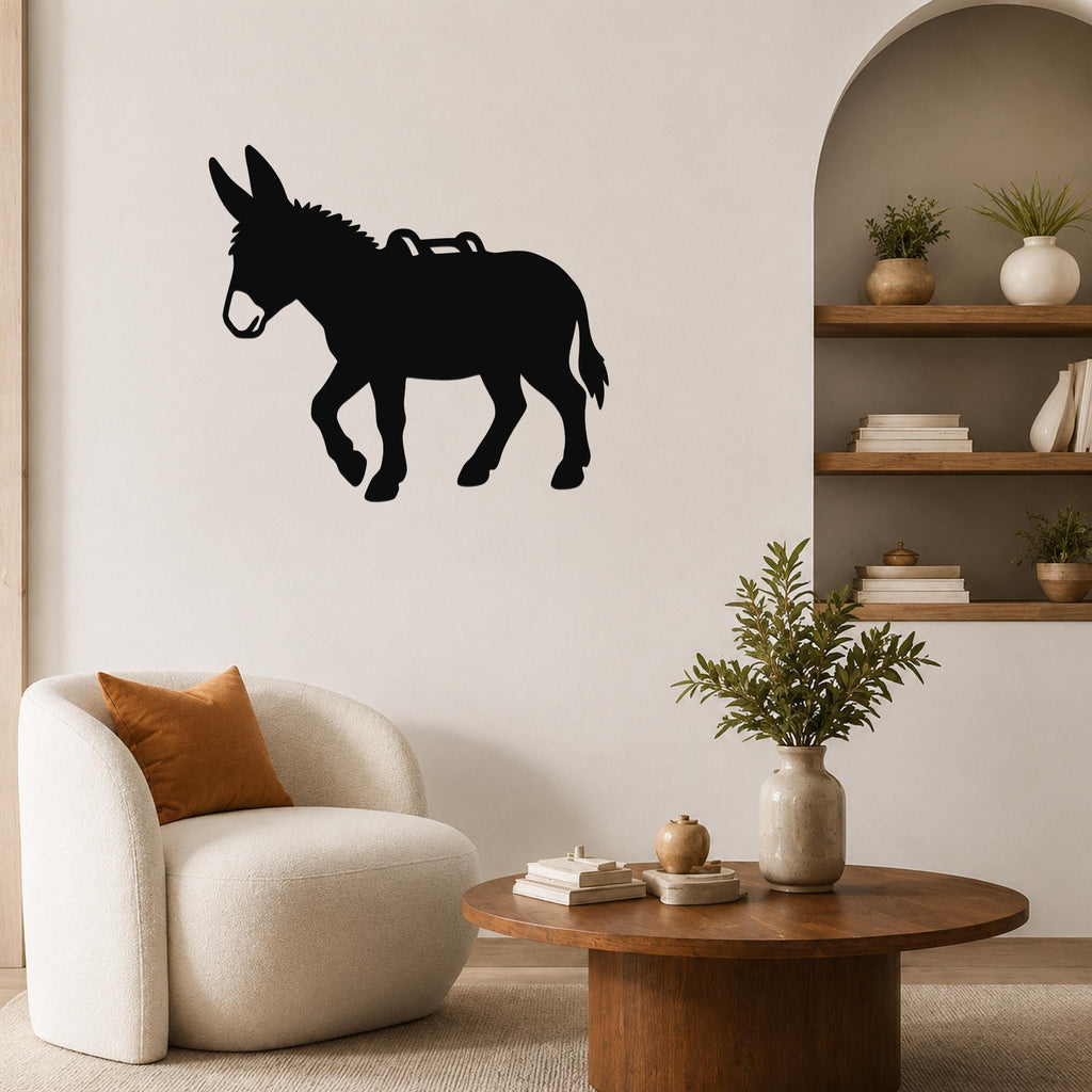 Black metal burro wall art silhouette with saddle cutout, mounted on a living room wall above a white armchair.