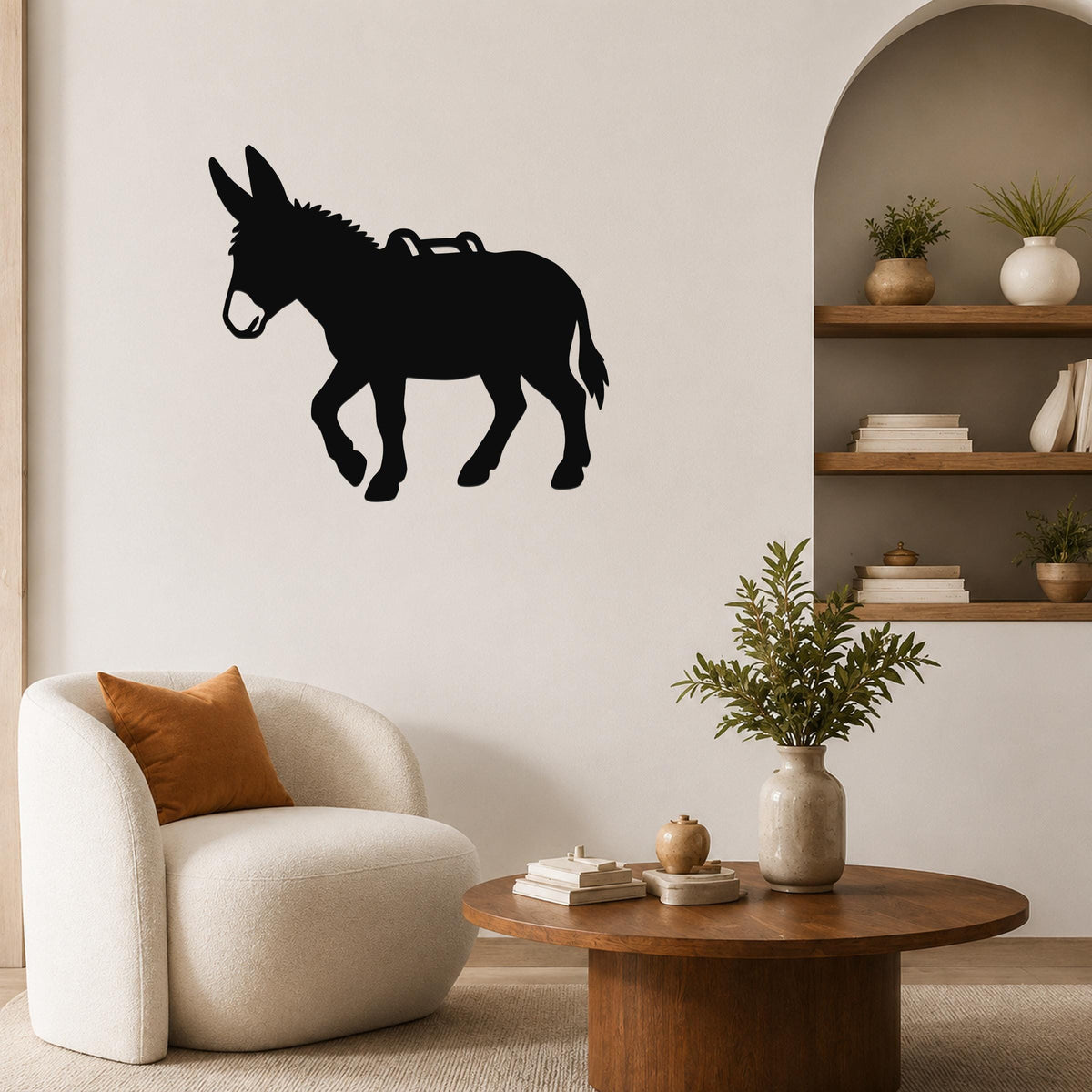 Black metal burro wall art silhouette with saddle cutout, mounted on a living room wall above a white armchair.