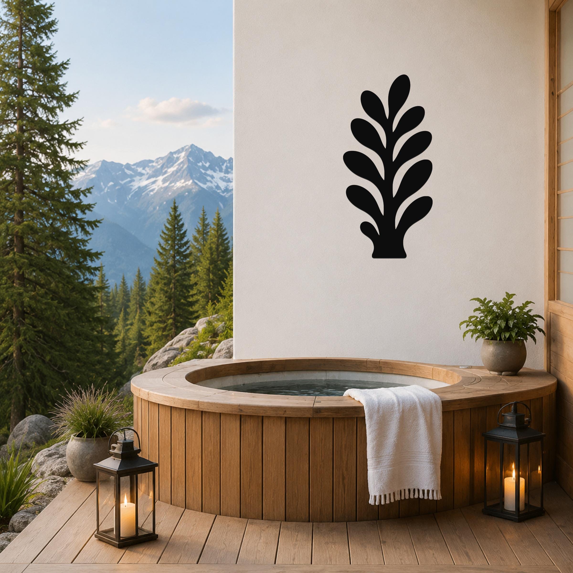 Black metal wall art in a leafy sprig silhouette, mounted on a white wall above a wooden hot tub on a mountain-view deck.