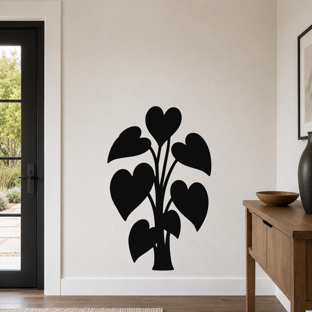 Black metal wall art in the silhouette of a philodendron with heart-shaped leaves, mounted on a living room wall above a wooden console table.