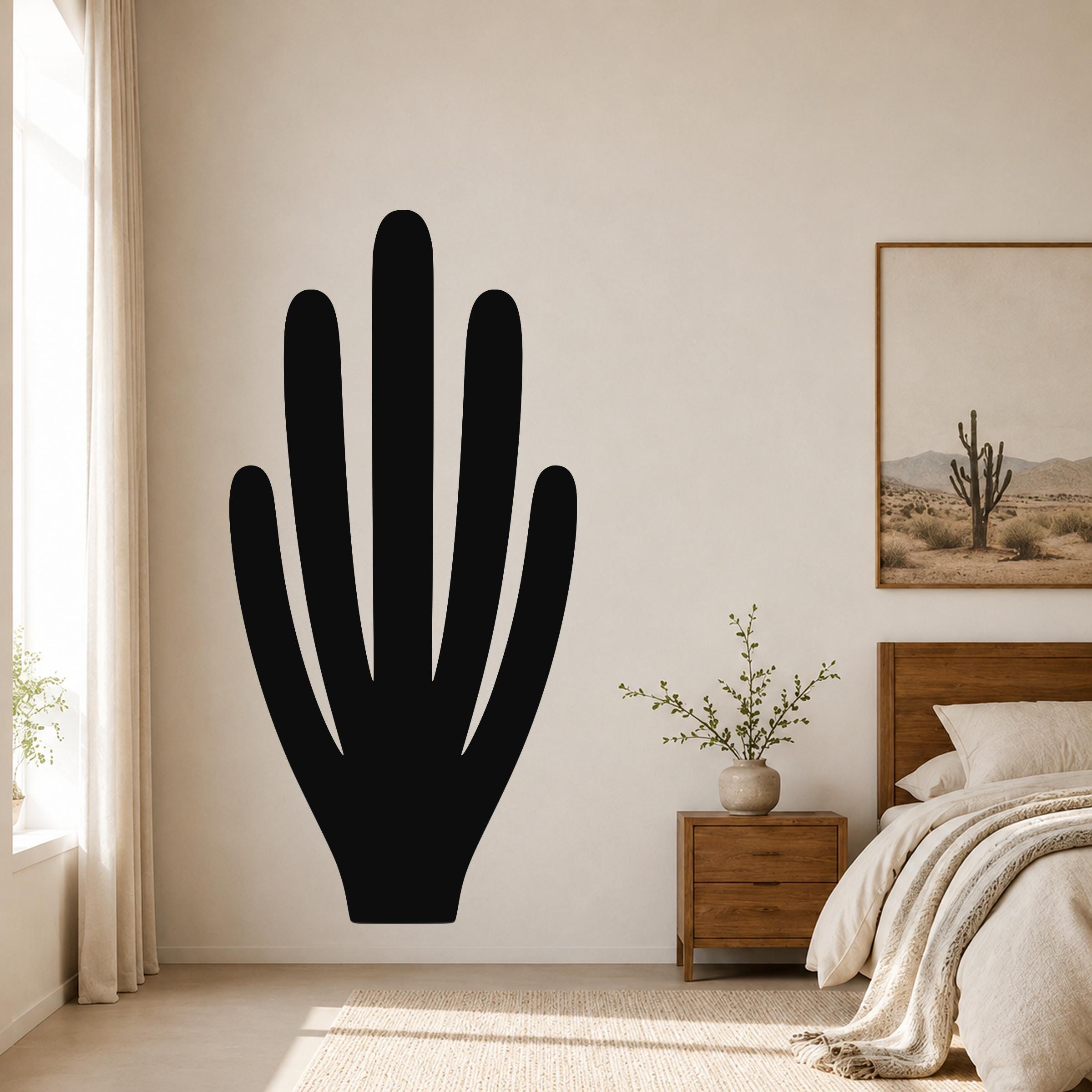 Black metal wall art in the silhouette of an organ pipe cactus, mounted on a bedroom wall above a nightstand.