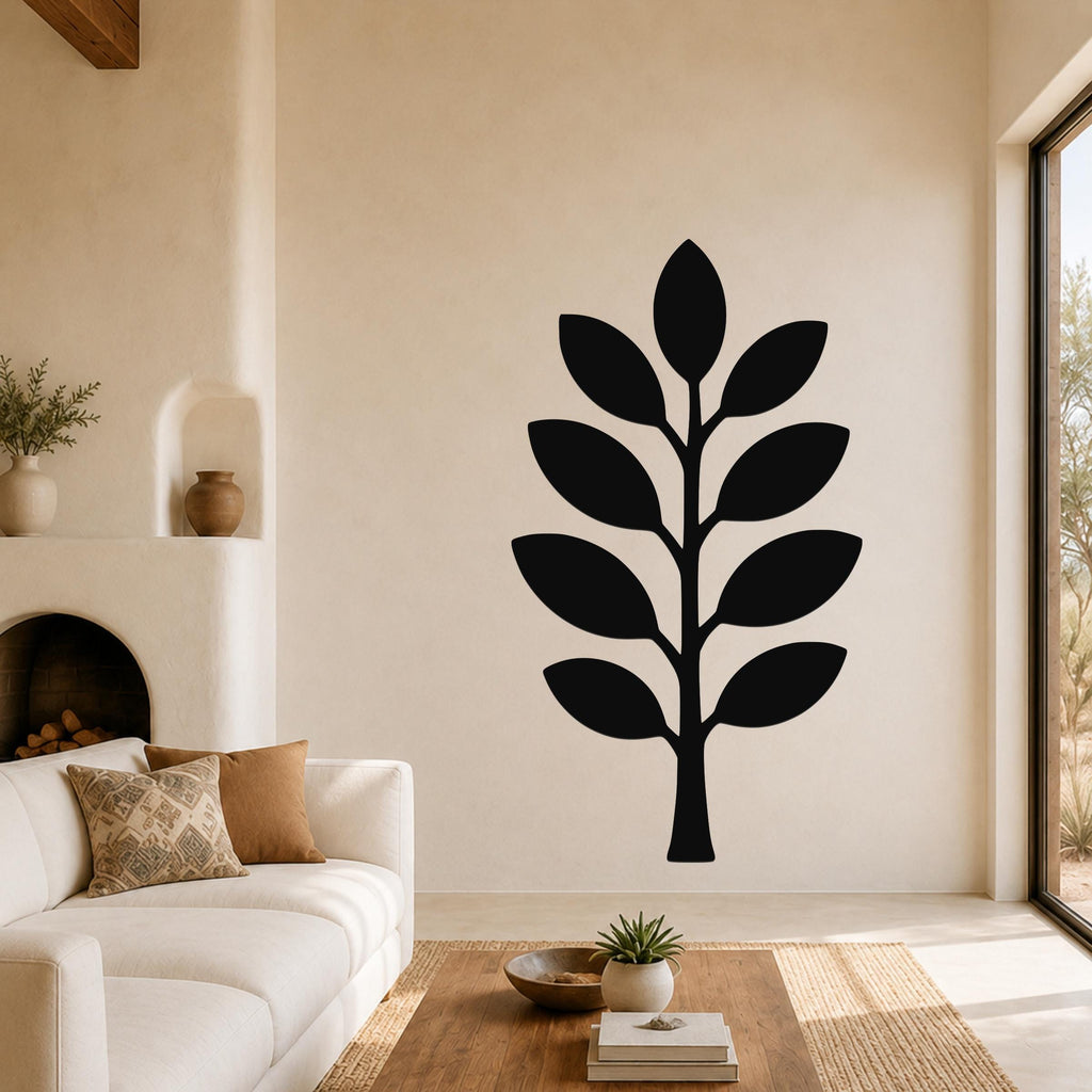 Black metal olive branch wall art with leaf cutouts, mounted on a living room wall above a sofa.