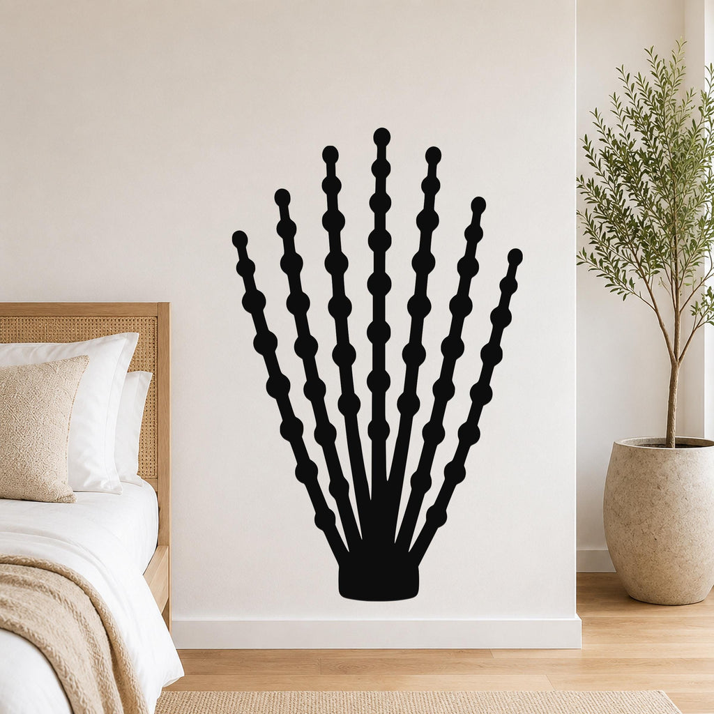 Black metal ocotillo wall art with beaded branch cutouts, mounted on a bedroom wall above a bed.
