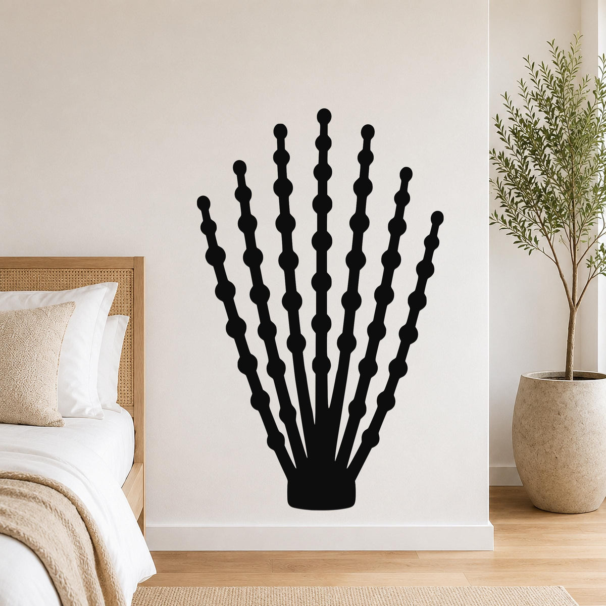 Black metal ocotillo wall art with beaded branch cutouts, mounted on a bedroom wall above a bed.