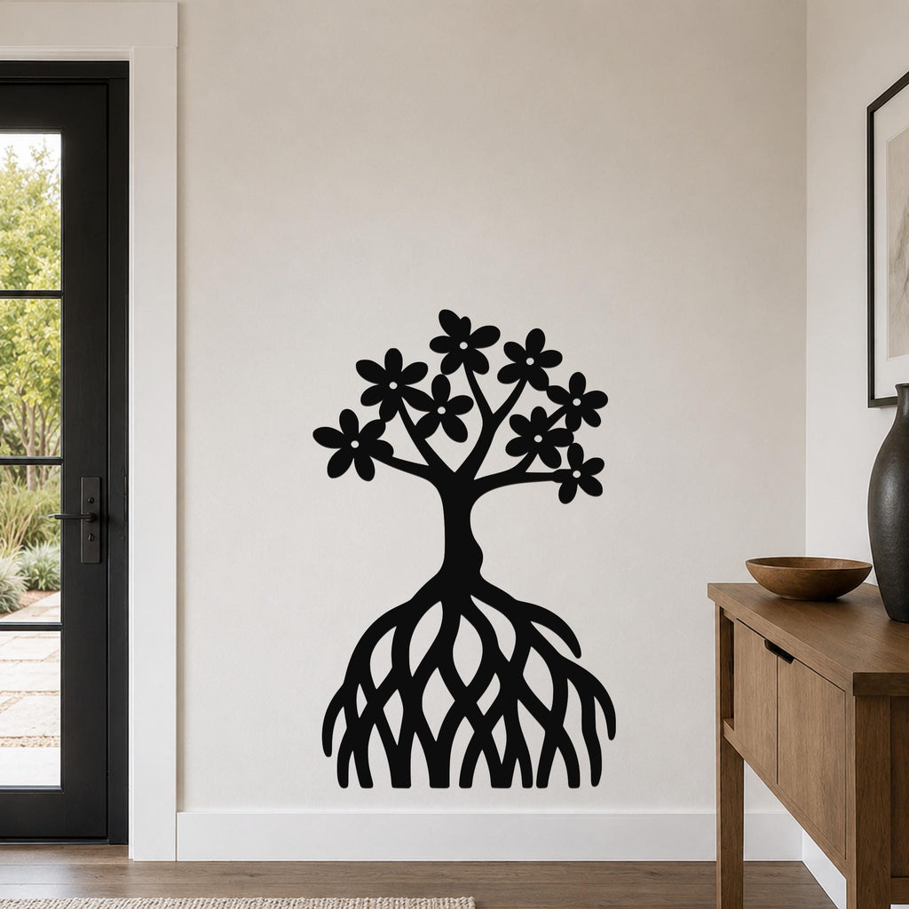 Black metal wall art cutout of a tree with flowers and exposed roots, mounted on a white wall in a living room.