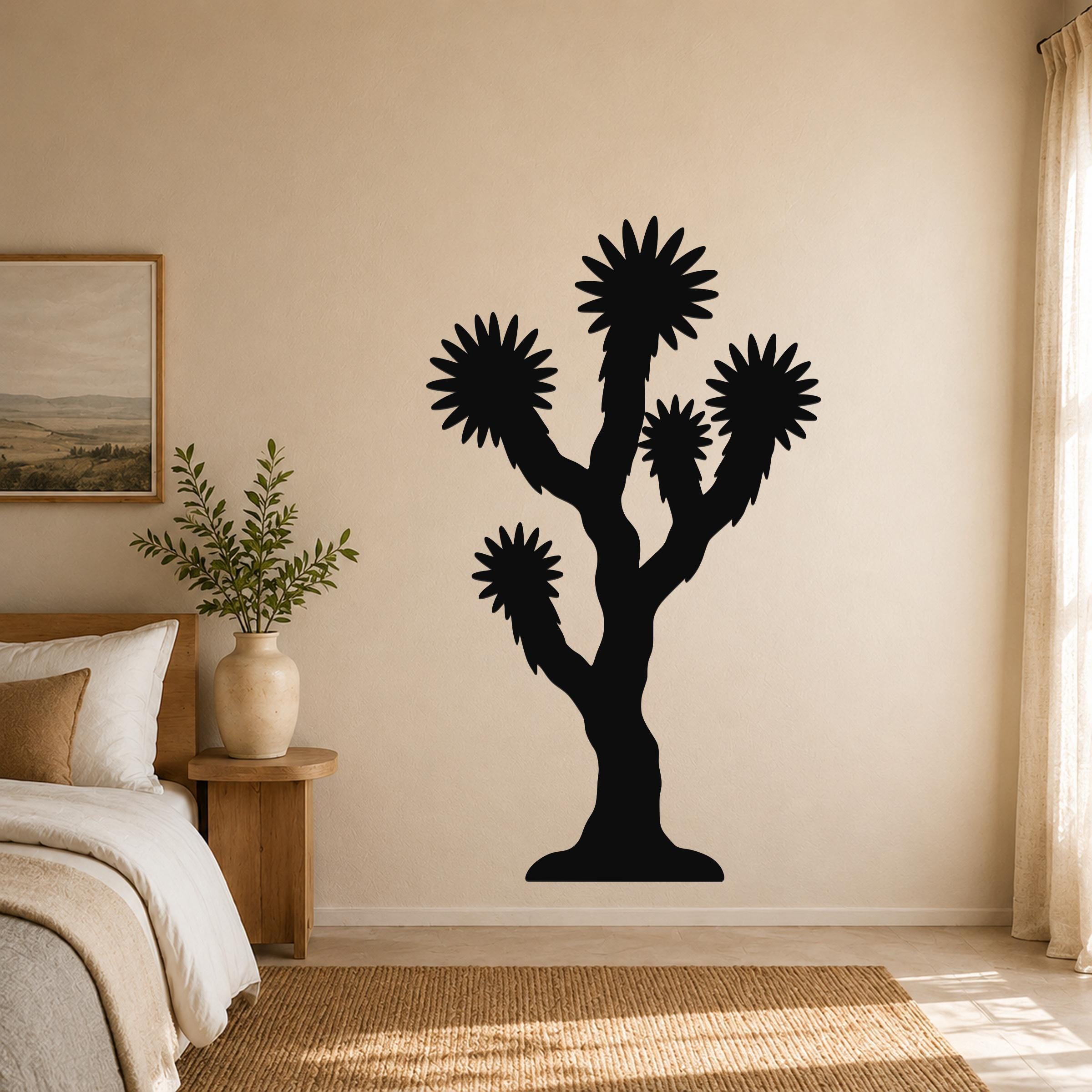 Black metal Joshua tree wall art with starburst-shaped branches, mounted on a beige bedroom wall above a wooden nightstand.