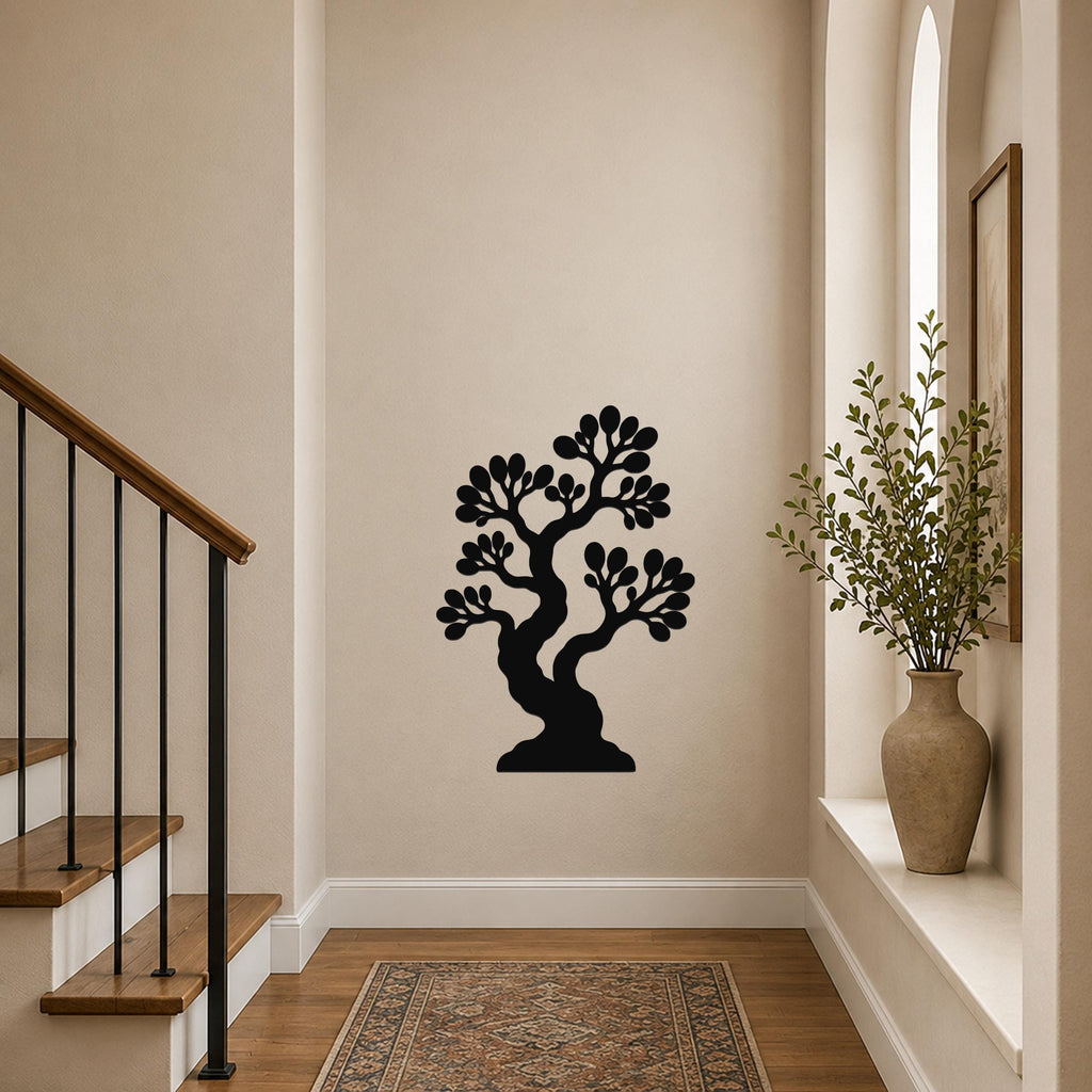 Black metal wall art of a bonsai tree silhouette with detailed branches and leaves, mounted on a hallway wall near a staircase and a window with a potted plant.