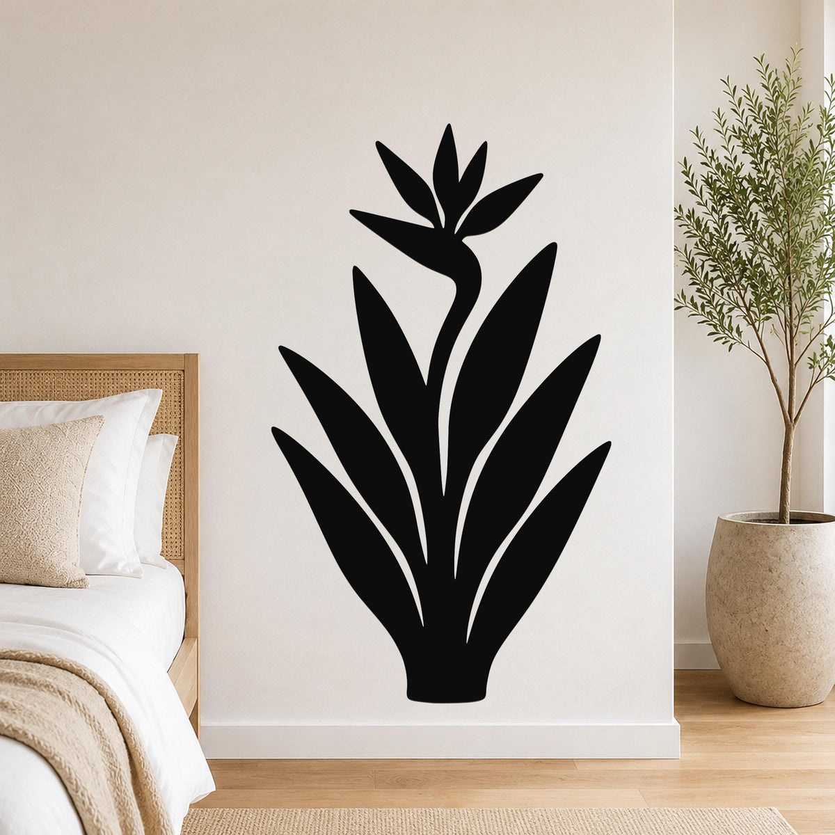 Black metal Bird of Paradise wall art silhouette with leaf and flower cutouts, mounted on a white bedroom wall above a bed.