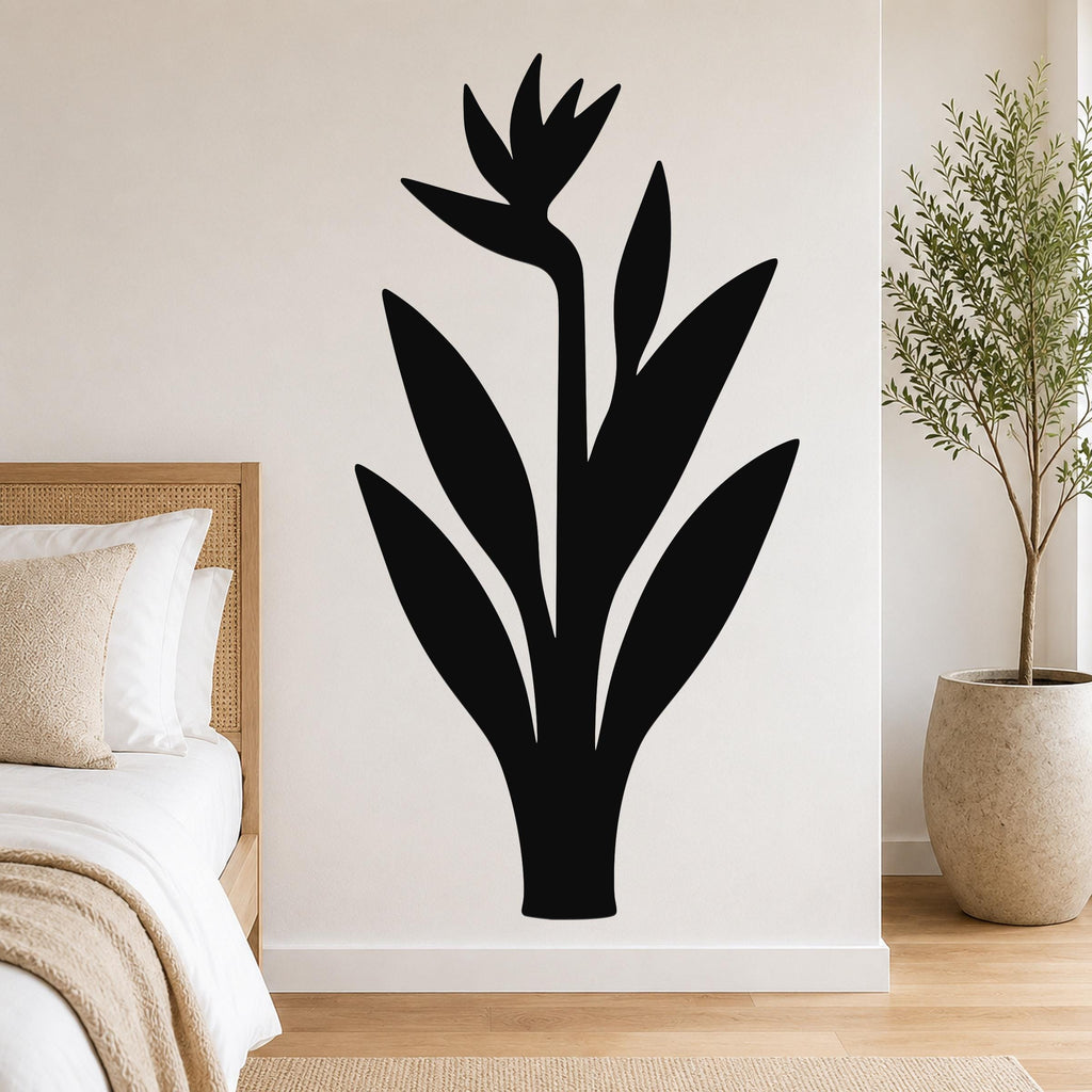 Black metal Bird of Paradise wall art silhouette with leaf and flower cutouts, mounted on a bedroom wall above a bed.