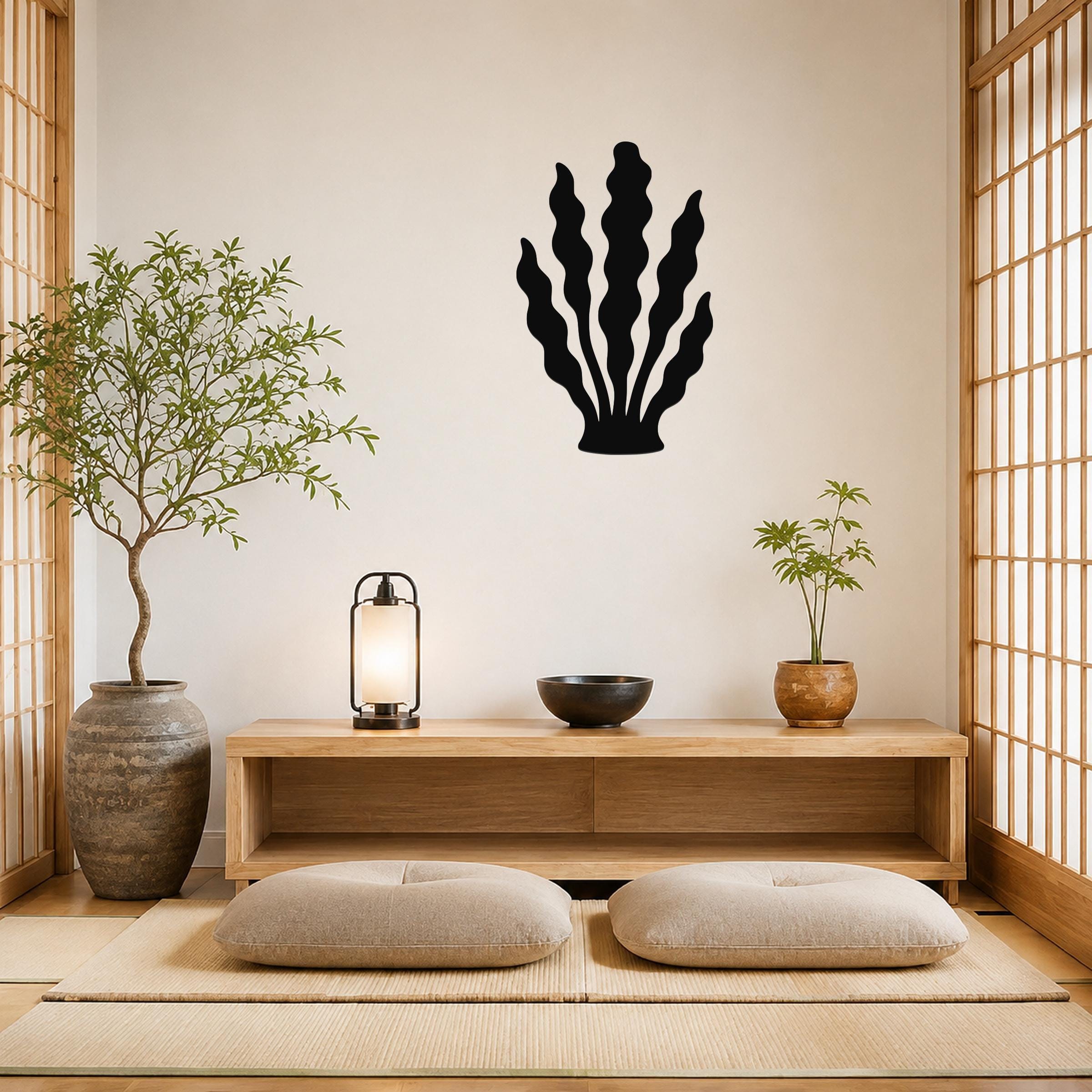 Black metal kelp wall art with wavy leaf cutouts, mounted on a light wall above a wooden console in a minimalist living room.