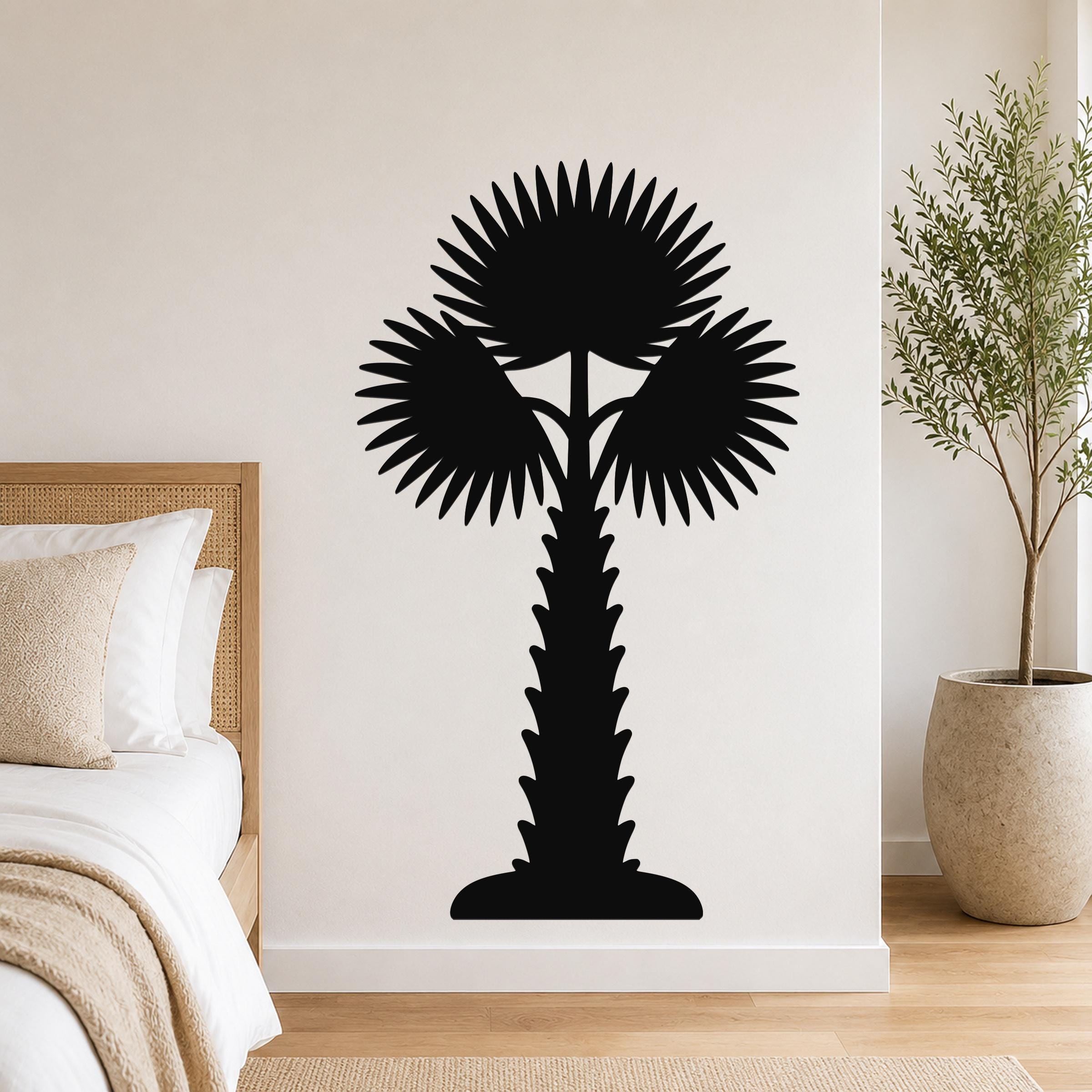 Black metal palm tree wall art with fan-shaped fronds and a textured trunk, mounted on a white wall above a bed in a bedroom.
