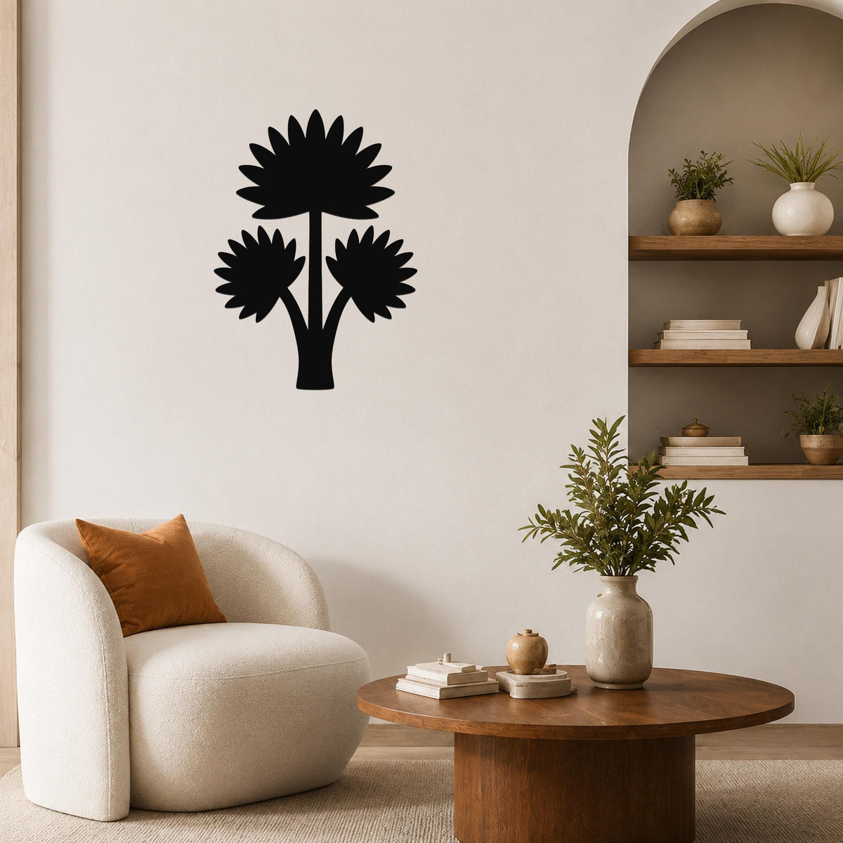Black metal wall art featuring a fan palm tree silhouette with three flower-like shapes, mounted on a living room wall above a round wooden coffee table.