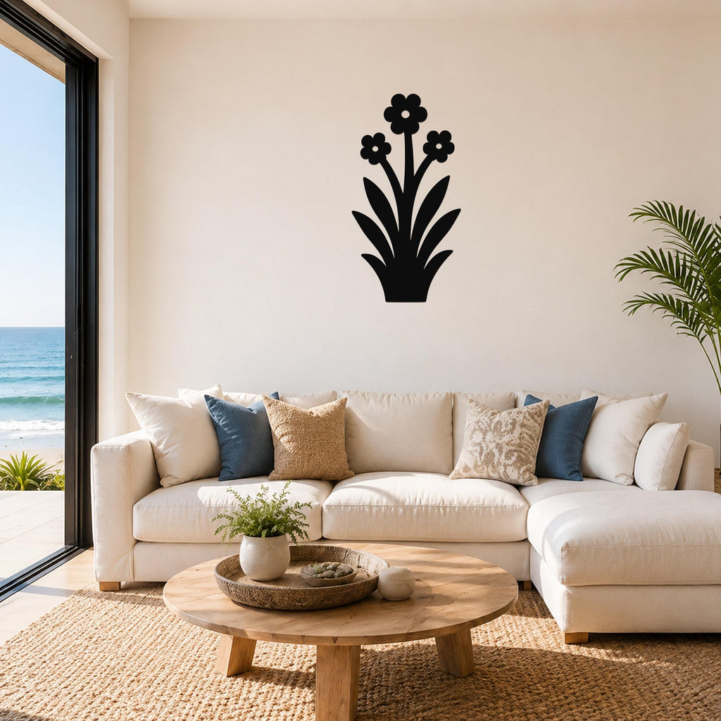 Black metal wall art with a floral silhouette of three flowers and leaves, mounted on a living room wall above a white sofa.