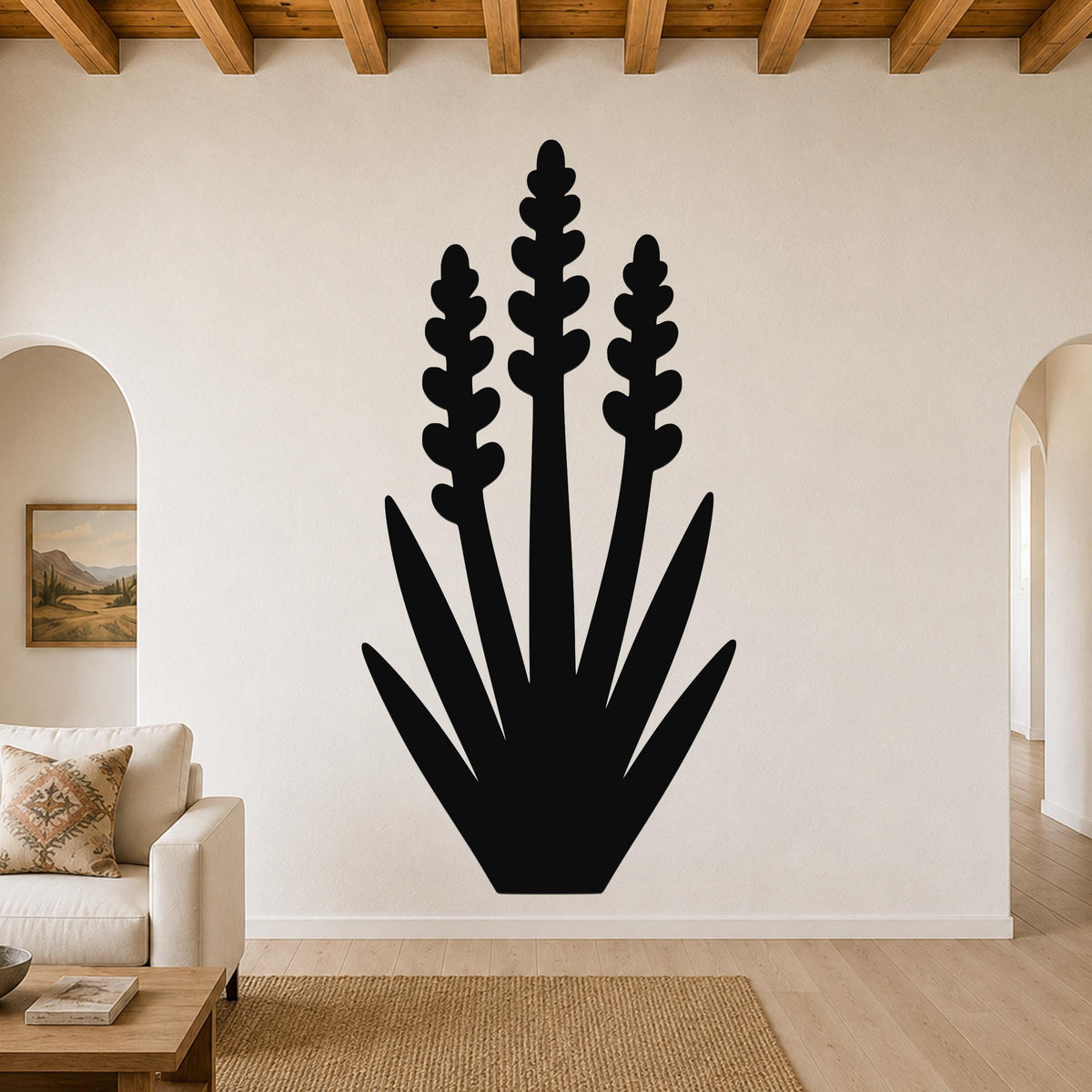 Black metal yucca wall art with layered leaf and bloom cutouts, mounted on a living room wall above a sofa.