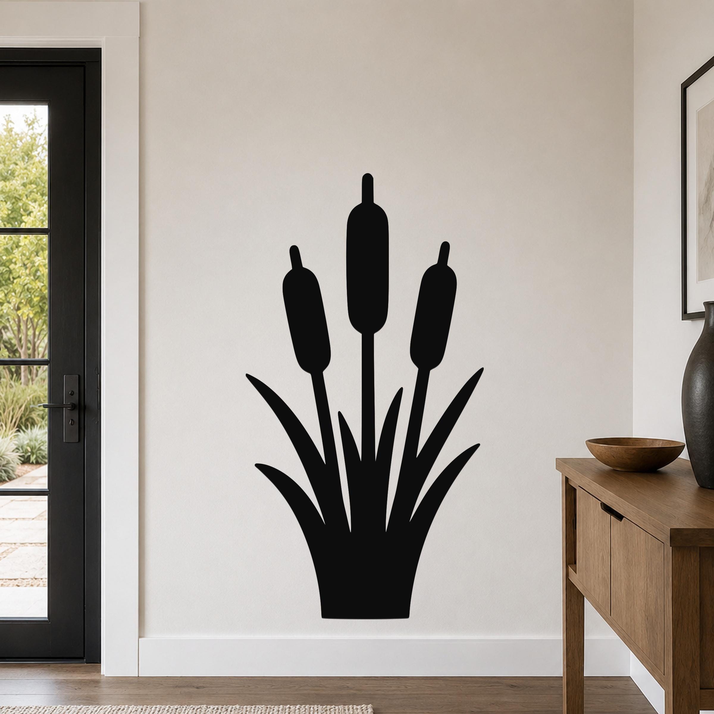 Black metal cattail wall art silhouette with three seed heads and leafy base, mounted on a living room wall above a wooden console table.