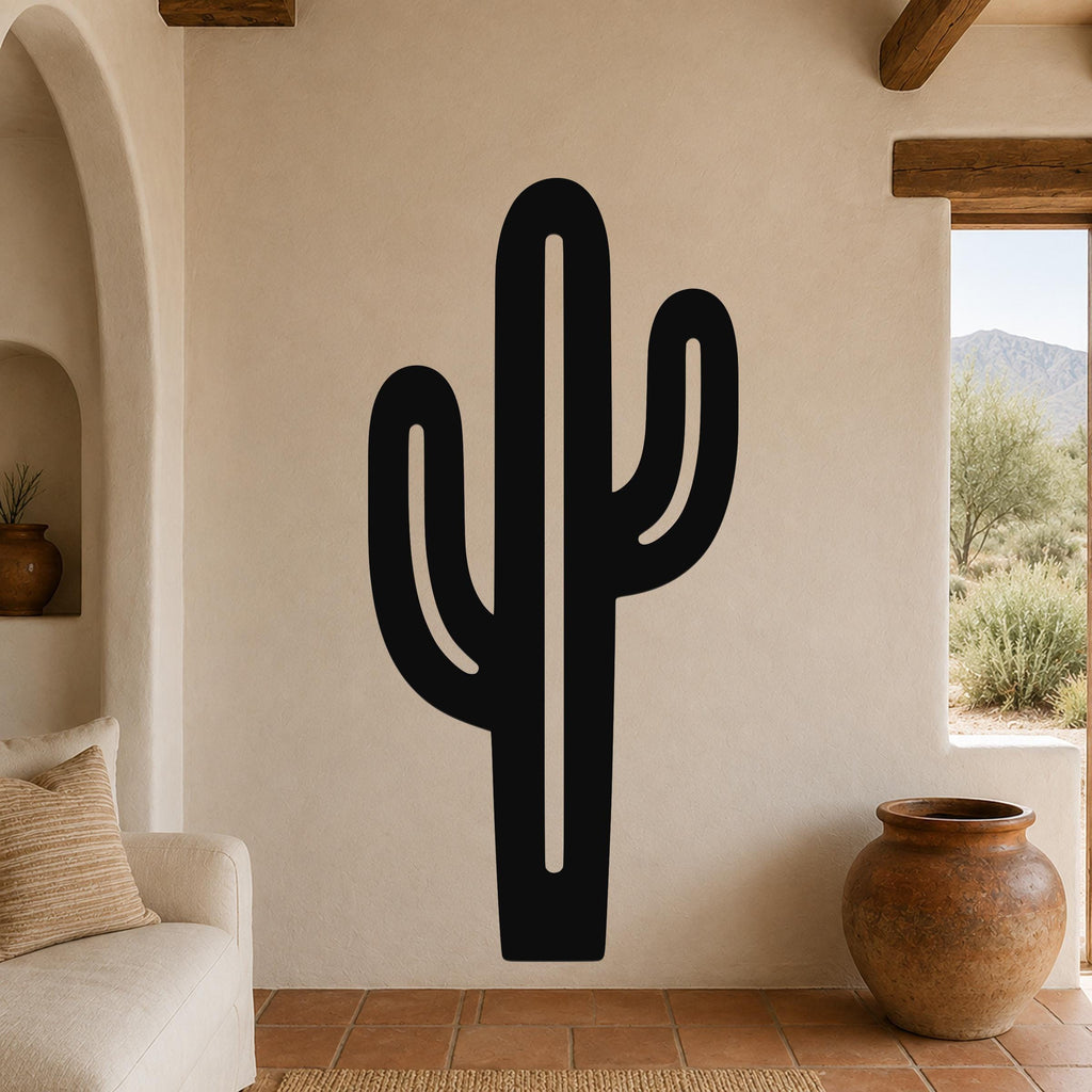 Black metal saguaro cactus wall art with cutout arms, mounted on a beige living room wall above a sofa.