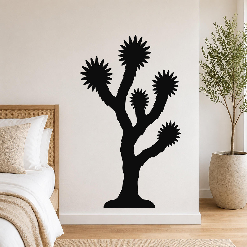 Black metal Joshua tree wall art with starburst-shaped branches, mounted on a bedroom wall above a bed.