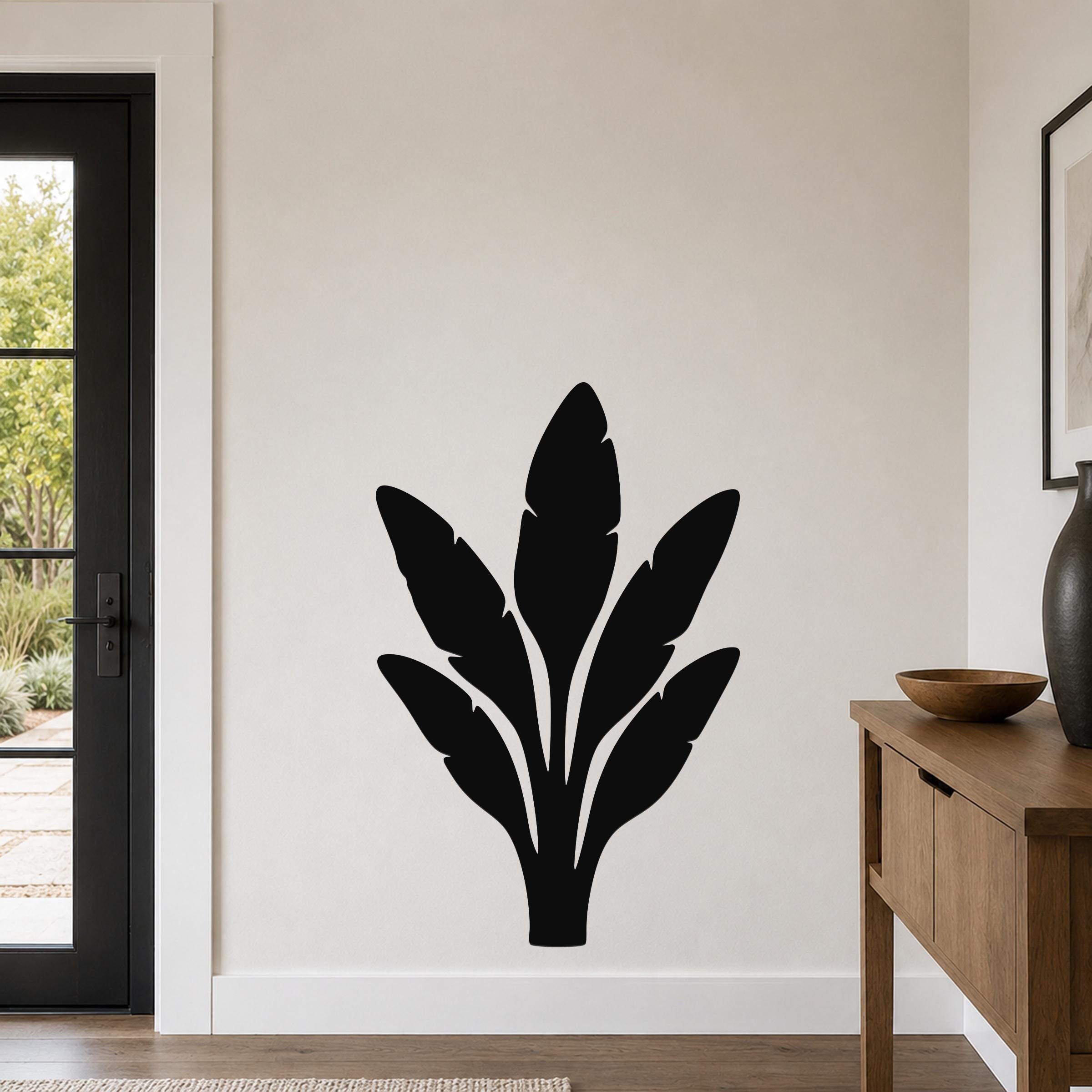 Black metal banana plant wall art with leaf cutouts, mounted on a light-colored wall in a modern entryway.