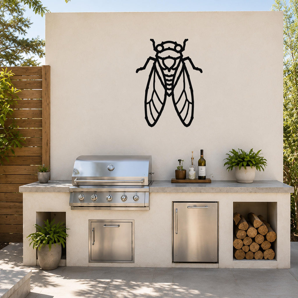 Black metal cicada wall art with detailed wing cutouts, mounted on an outdoor kitchen wall above a stainless steel grill.
