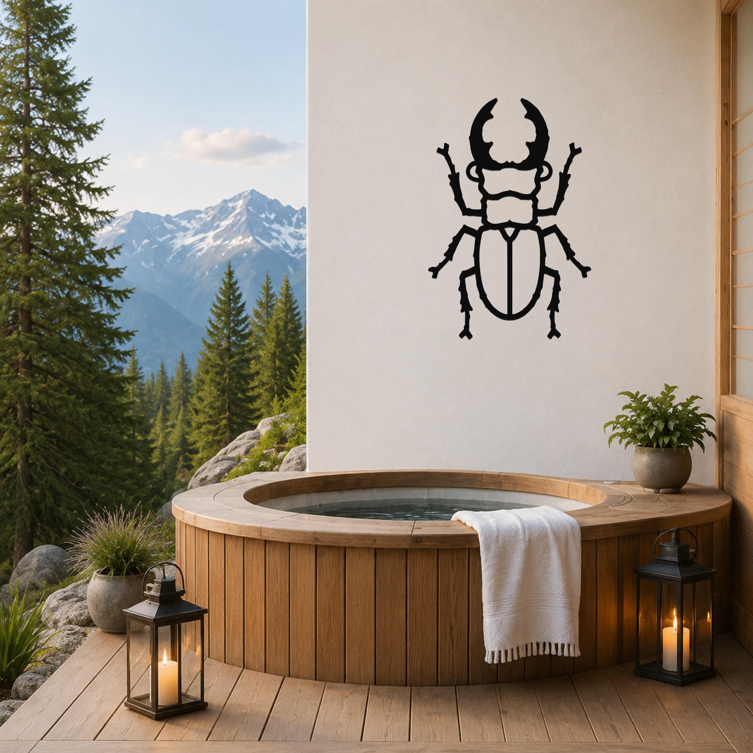 Black metal beetle wall art with detailed cutout features, mounted on a white wall above a wooden hot tub on a mountain-view deck.