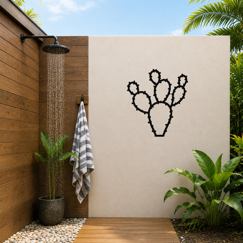 Black metal cactus wall art with spiny cutout details, mounted on a beige outdoor wall beside a wooden shower area.
