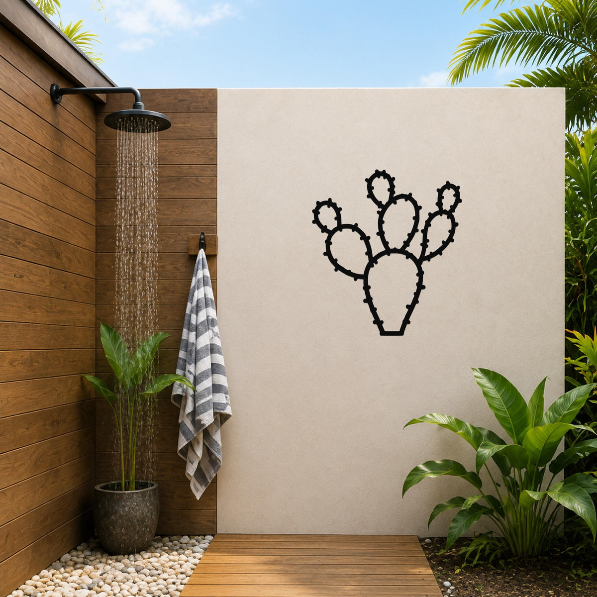 Black metal cactus wall art with spiny cutout details, mounted on a beige outdoor wall beside a wooden shower area.