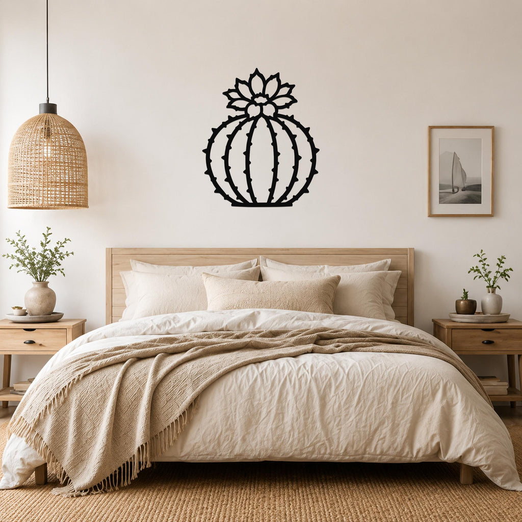 Black metal barrel cactus wall art with flower and spine cutouts, mounted above a bed in a neutral bedroom.