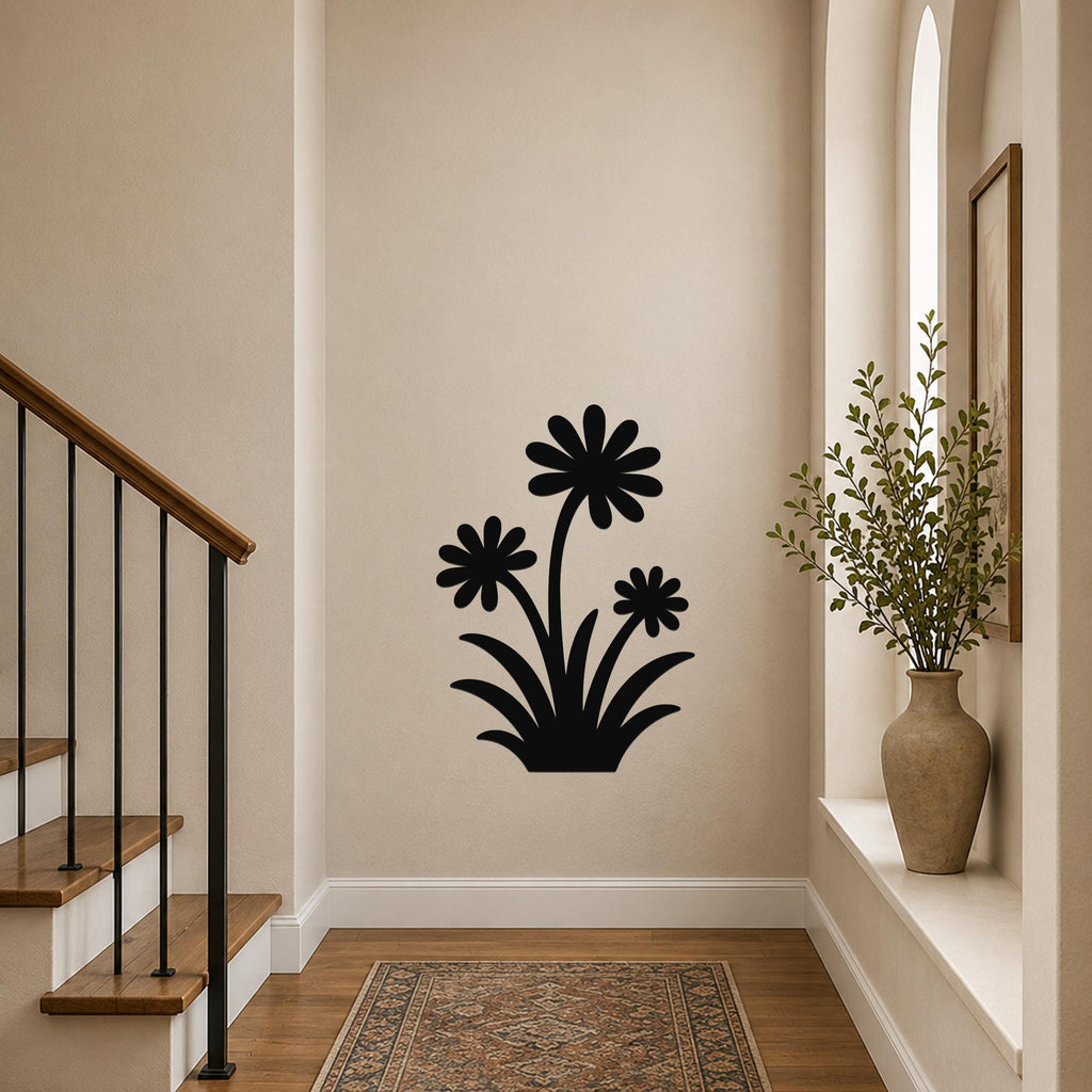 Black metal wall art with a wildflower silhouette of three daisies and leaves, mounted on a hallway wall near a staircase and a window with a potted plant.