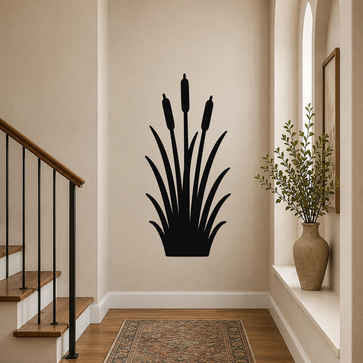 Black metal cattail wall art silhouette with three seed heads and long leaves, mounted on a hallway wall above a patterned rug near a staircase.