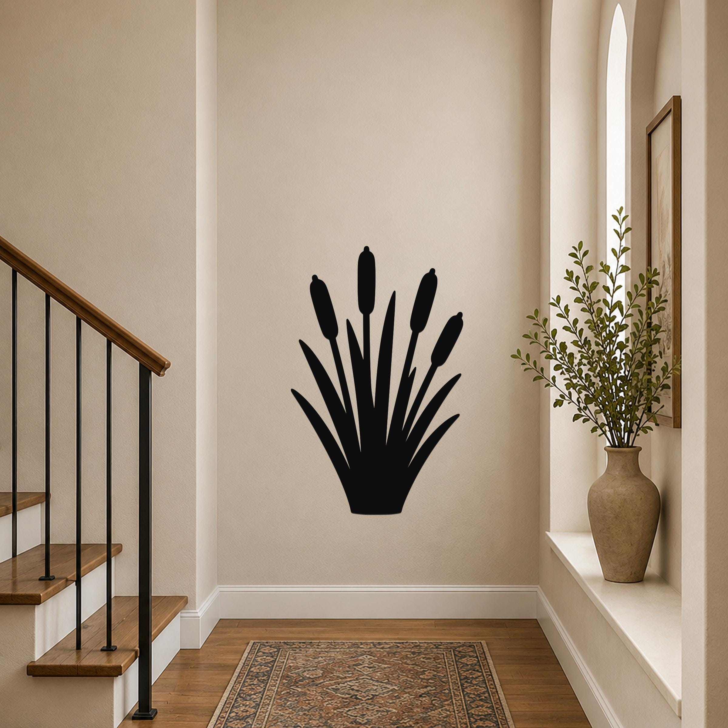 Black metal cattail wall art silhouette with multiple reed stems and leaves, mounted on a beige hallway wall near a staircase and window.
