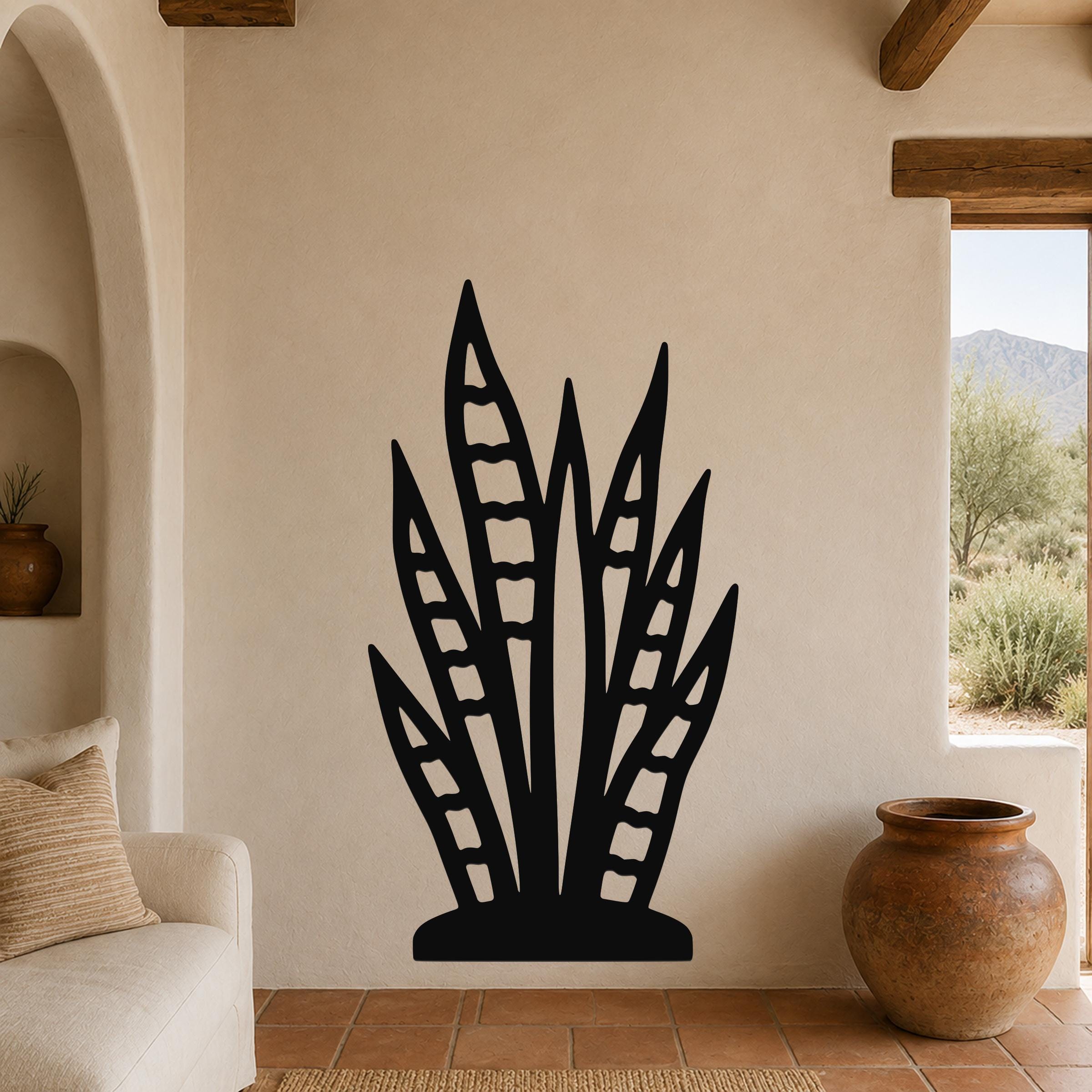 Black metal snake plant wall art with leaf cutouts, mounted on a beige living room wall above a sofa.