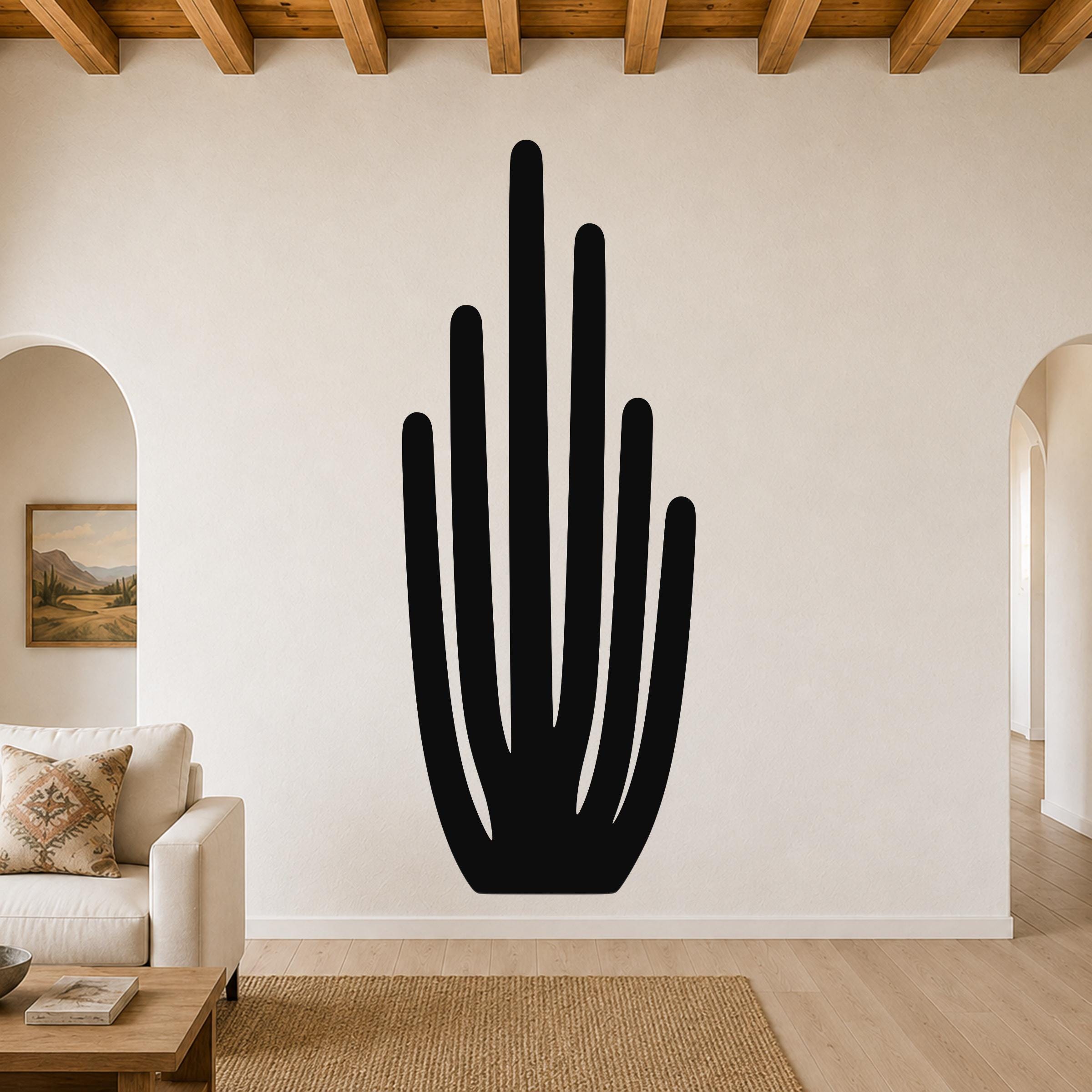 Black metal wall art in the shape of an organ pipe cactus, mounted on a living room wall above a sofa.