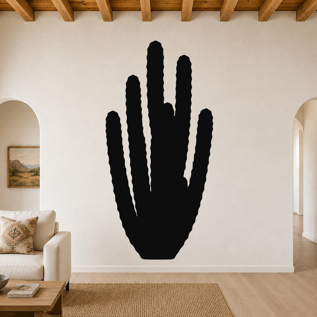 Black metal wall art in the shape of an organ pipe cactus with vertical ridges, mounted on a living room wall above a sofa.