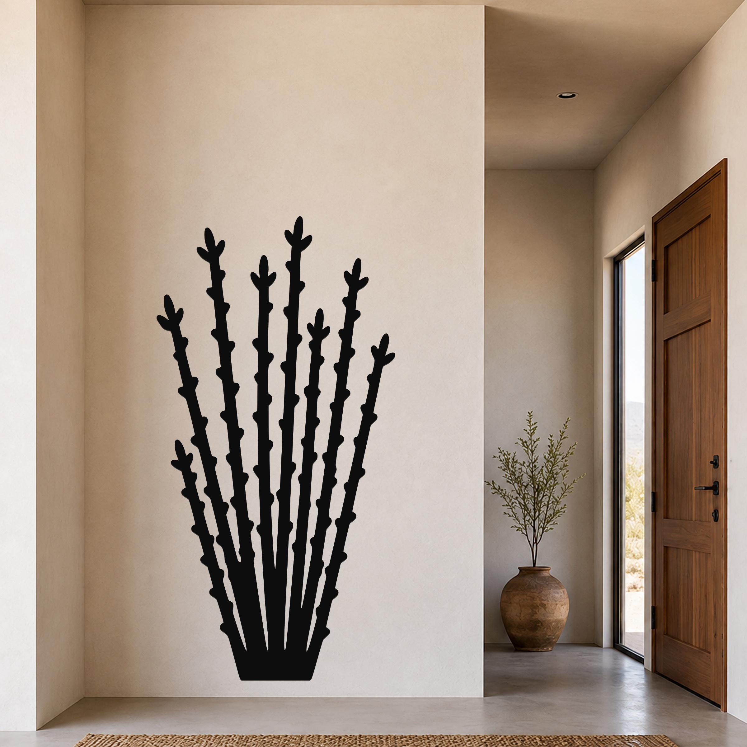 Black metal ocotillo wall art with tall, spiky branch cutouts, mounted on a beige wall in a modern entryway.