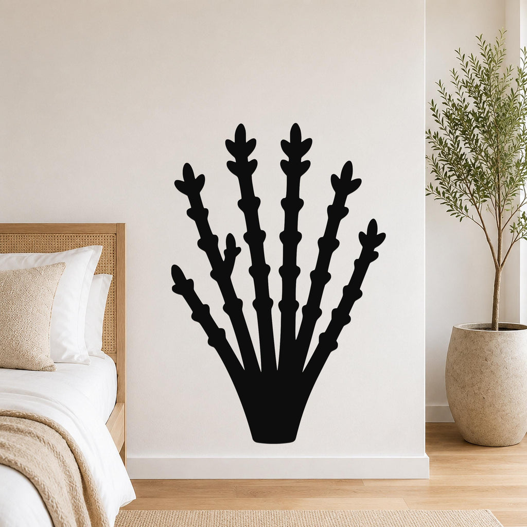 Black metal ocotillo wall art with branching cutouts, mounted on a bedroom wall above a bed.
