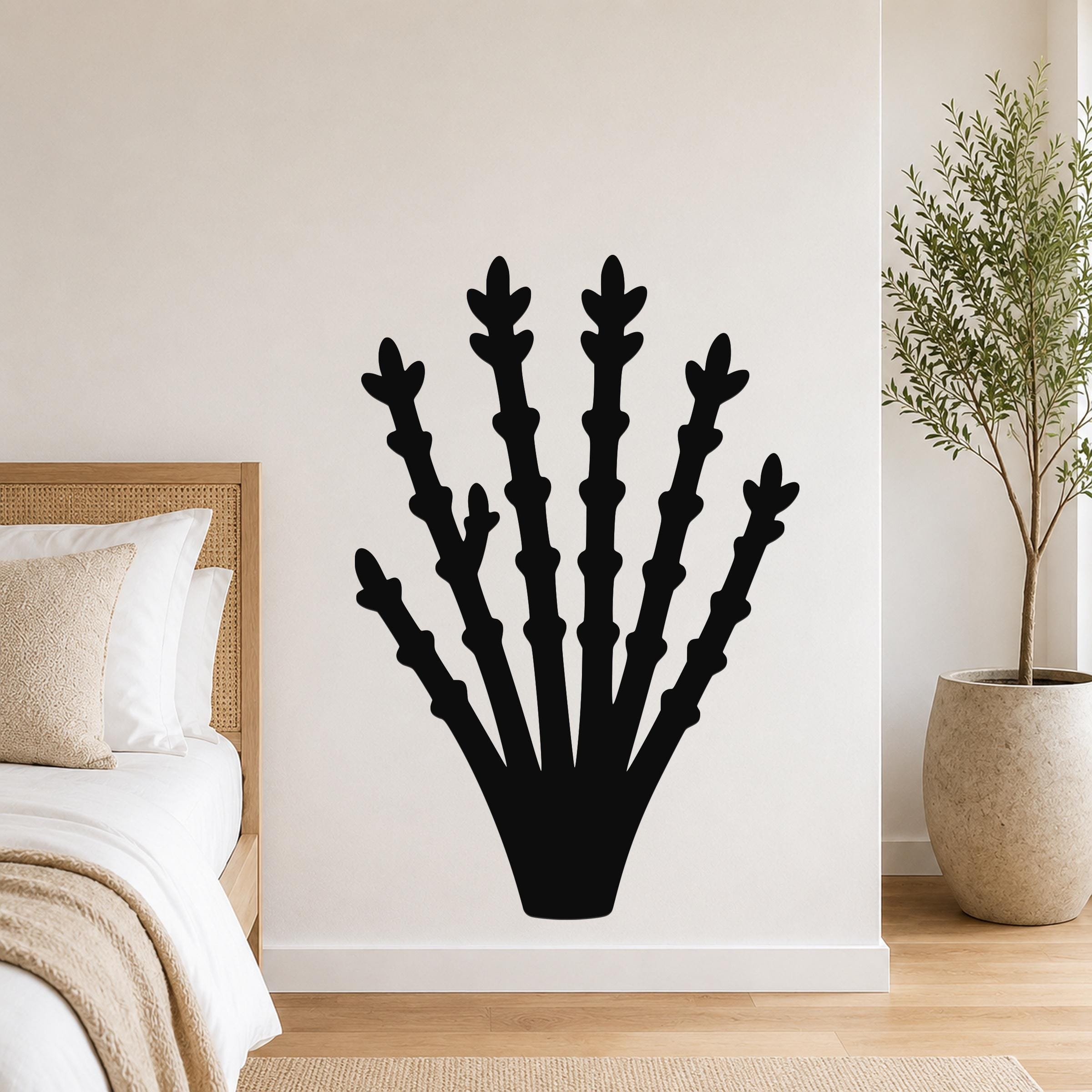 Black metal ocotillo wall art with branching cutouts, mounted on a bedroom wall above a bed.