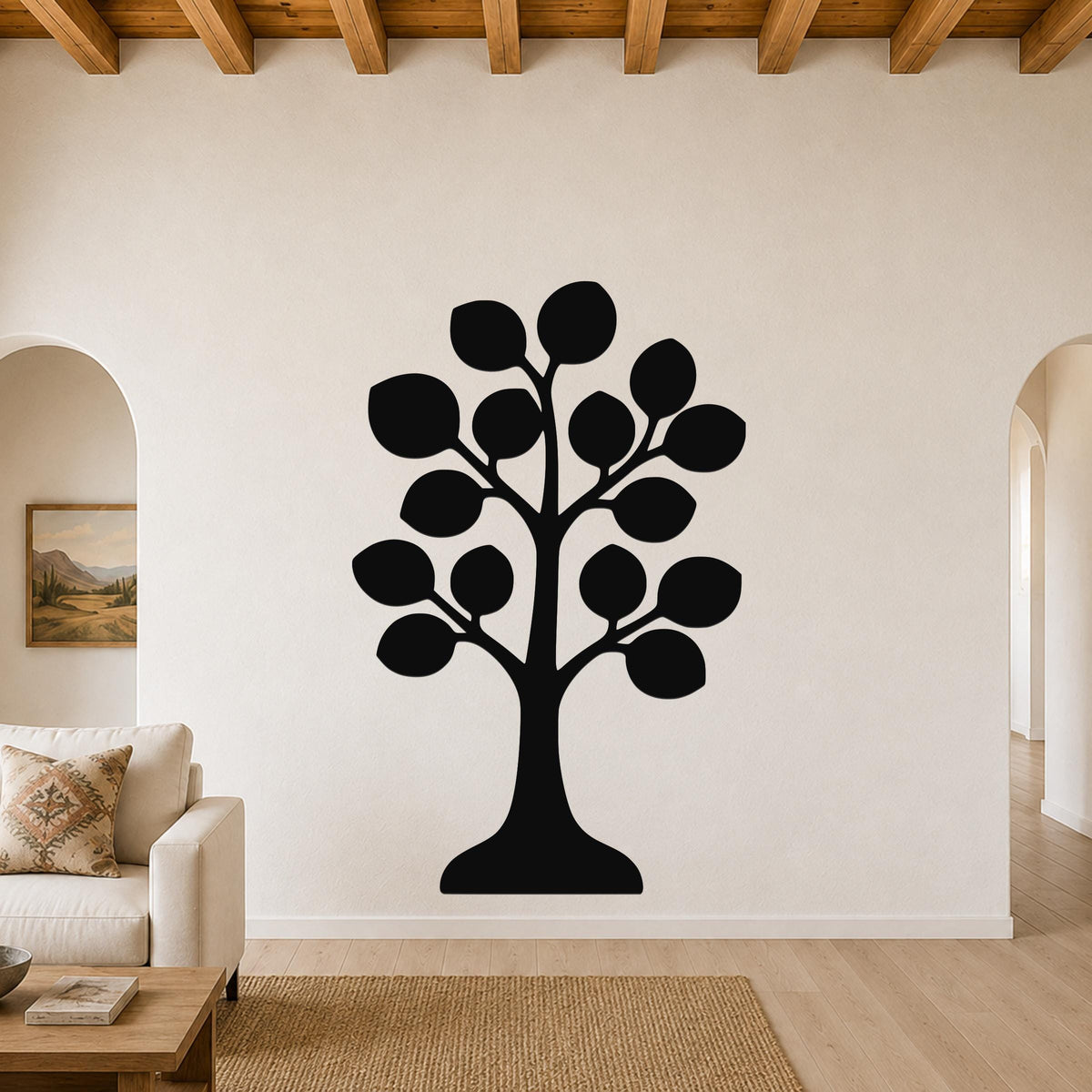 Black metal tree wall art with leaf cutouts, mounted on a living room wall above a sofa.