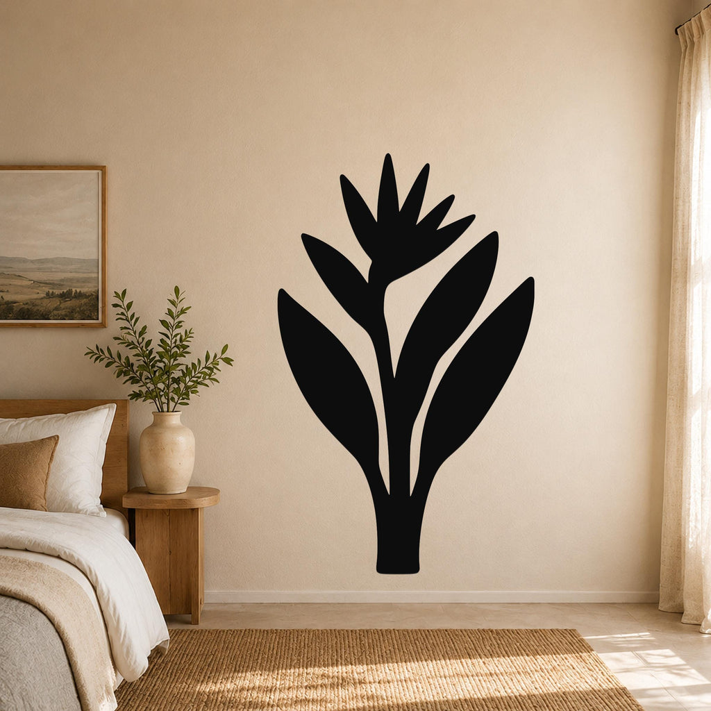 Black metal Bird of Paradise wall art silhouette mounted on a beige bedroom wall above a bed, with a wooden nightstand and framed landscape painting visible to the left.