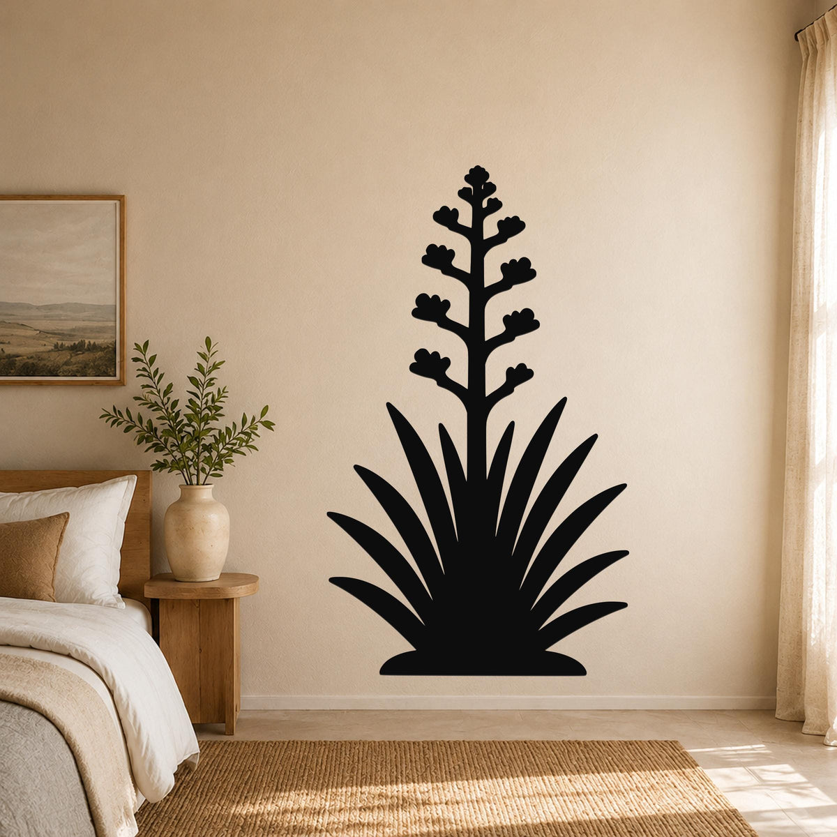 Black metal wall art in the silhouette of a blooming agave plant, mounted on a beige bedroom wall above a woven rug.