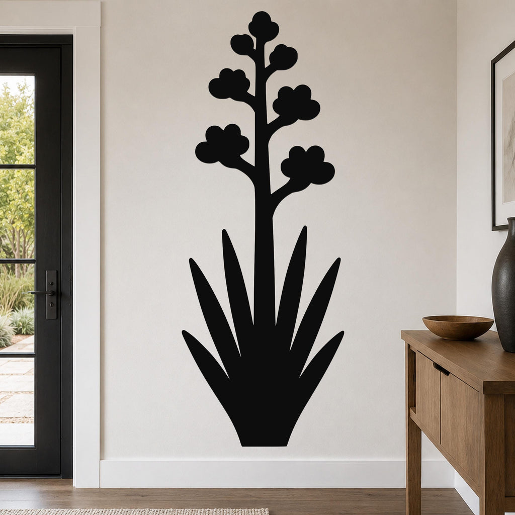 Black metal agave wall art with a blooming flower silhouette, mounted on a living room wall above a wooden console table.