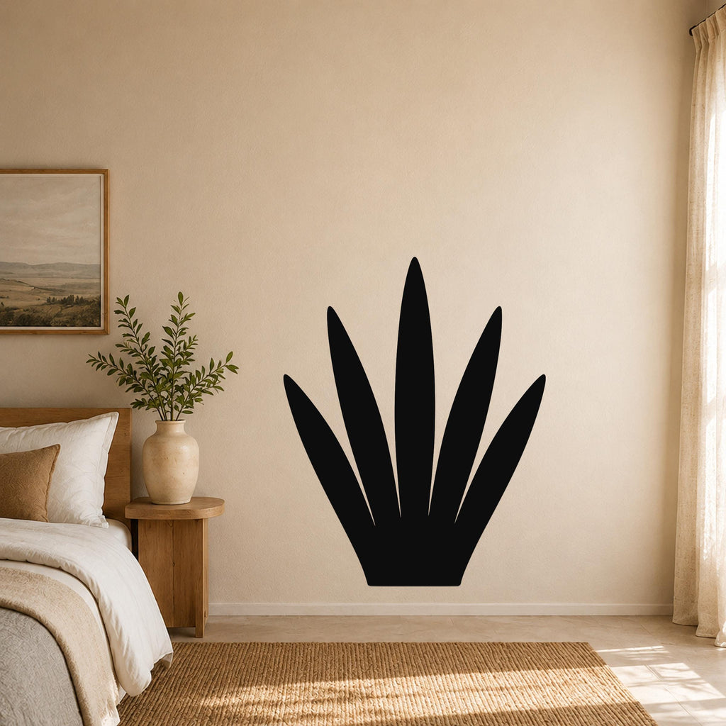 Black metal wall art in the shape of a century plant silhouette, mounted on a beige bedroom wall above a woven rug.