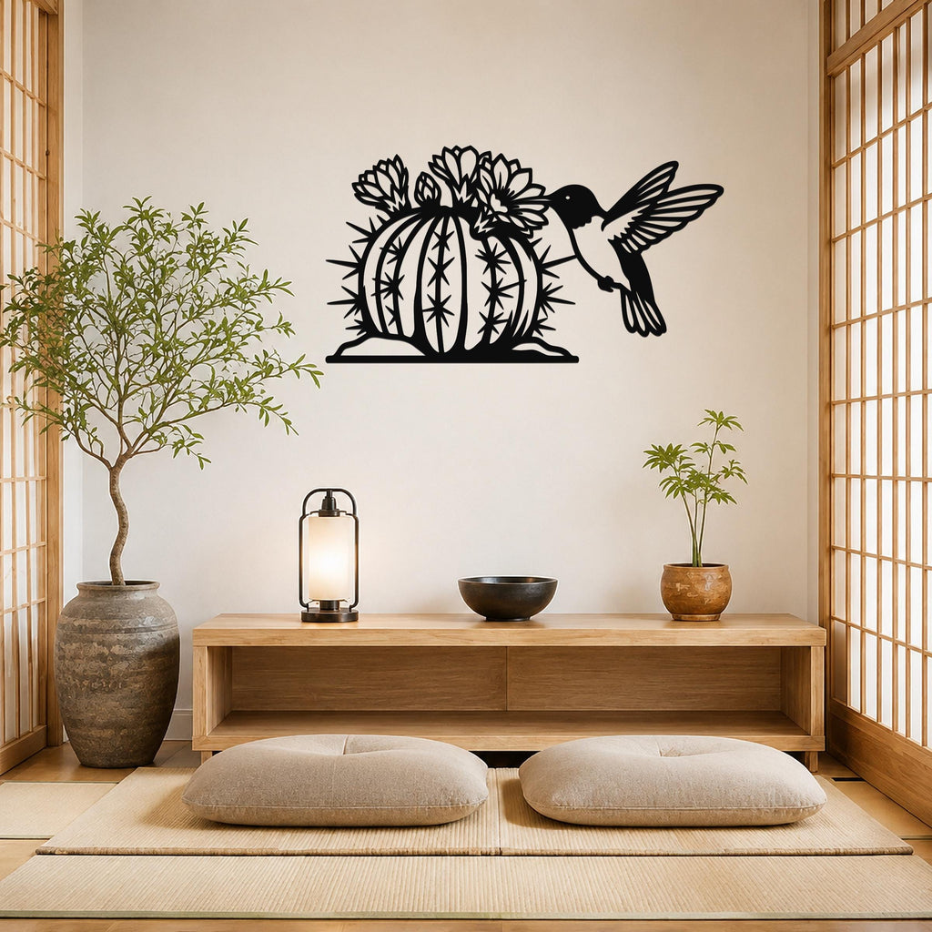Black metal wall art featuring a hummingbird and flowering barrel cactus cutout, mounted on a light-colored wall above a wooden console in a minimalist room.