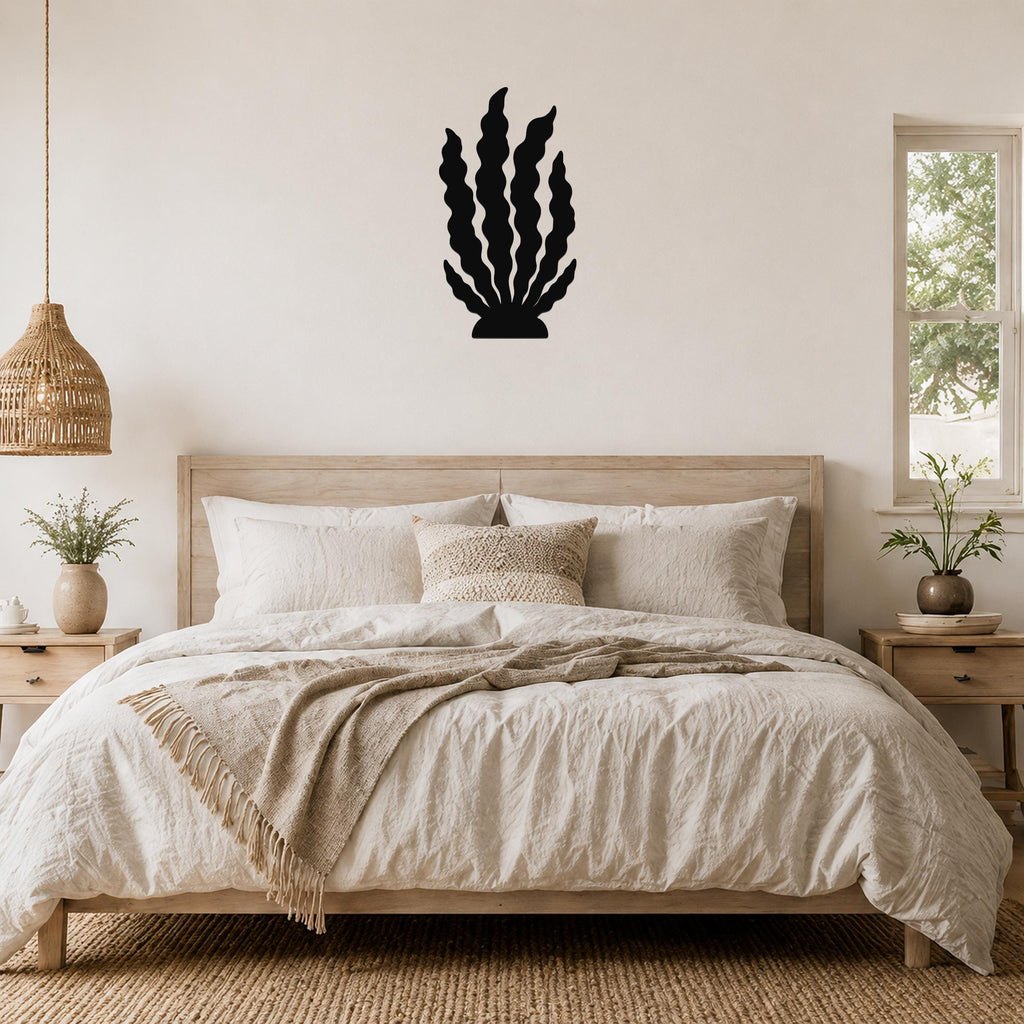 Black metal kelp wall art with wavy leaf cutouts, mounted above a wooden bed in a neutral bedroom.